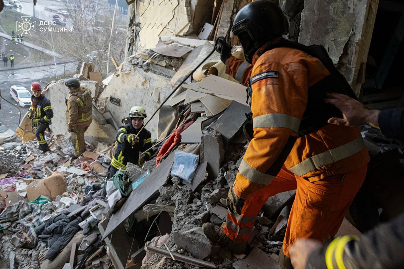 In this photo provided by the Ukrainian Emergency Service, rescuers search for civilians who were killed when a Russian drone hit an apartment building in Sumy, Ukraine, Thursday, Jan. 30, 2025. (Ukrainian Emergency Service via AP)