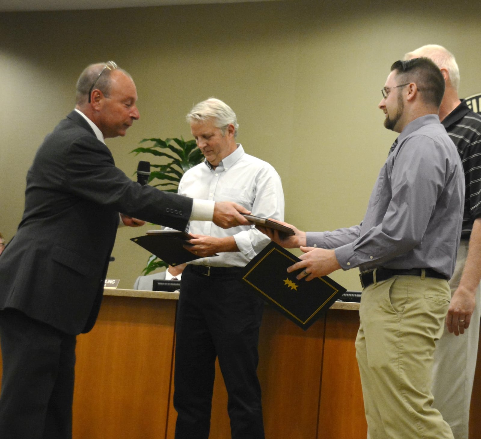 Fairfield Mayor Steve Miller hands Joshua Higgns a proclamation recognizing his actions in saving the life of Charlie Fisher, behind Higgins. Fisher suffered a cardiac arrest on May 18 at the end of a bicycle ride. Higgns heard Fisher collapse and then ran to begin chest compression. Greg Uhler, center left, was on his way home from a bike ride when he rode up to the scene and began assisting Higgins until police and medics arrived. Higgins and Uhler both received proclamations and keys to the city for what Miller called “heroic” actions. MICHAEL D. PITMAN/STAFF