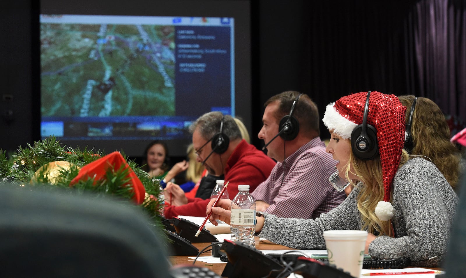 FILE - Santa tracker volunteer Meghan Huyck, right, and other volunteers answer phone calls from children all over the world at Peterson Air Force Base in Colorado Springs, Colo., Dec. 24, 2017. (Jerilee Bennett/The Gazette via AP, File)