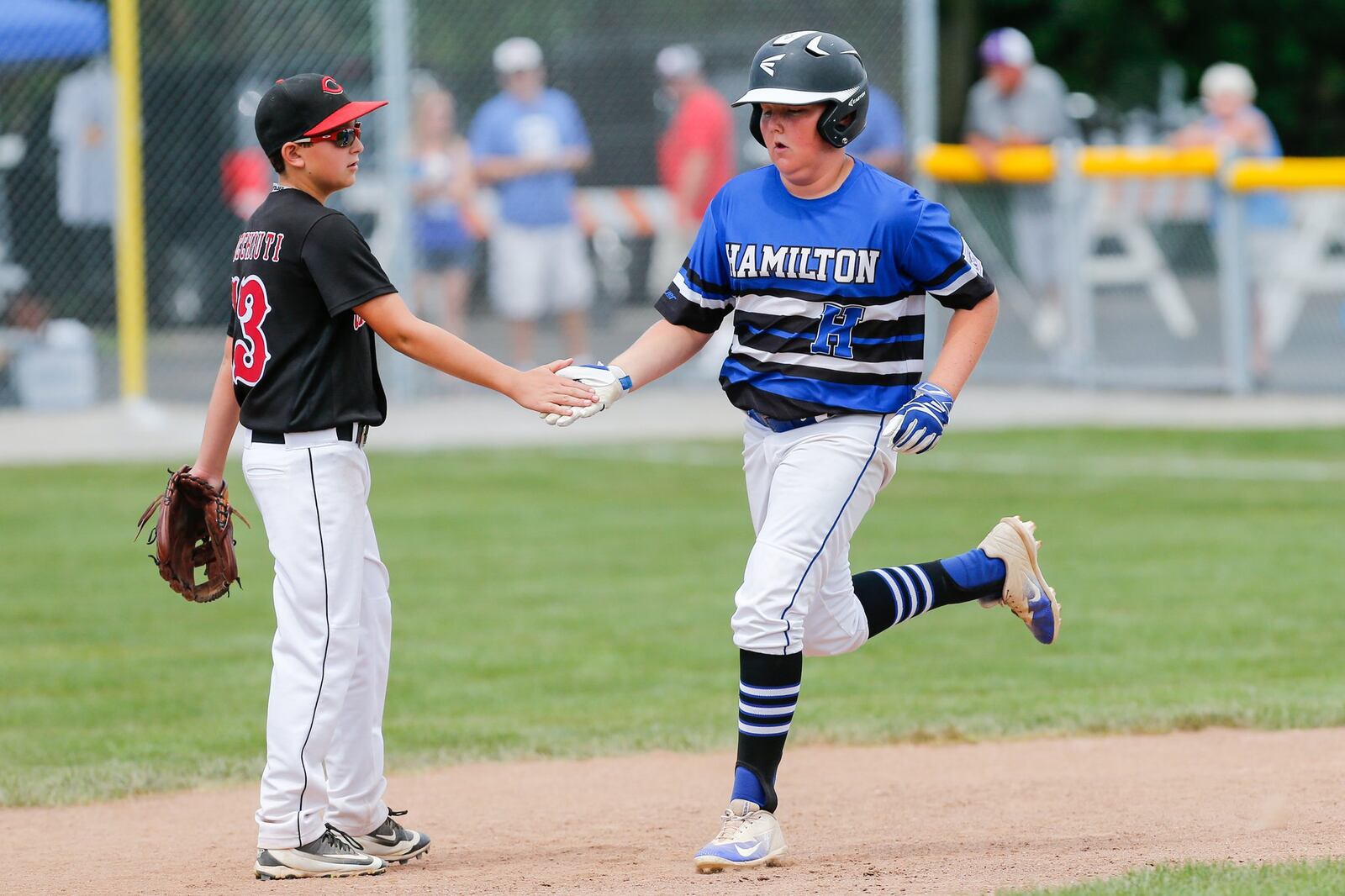 Hamilton West Side’s Casey Parsons is congratulated by Canfield’s Luca Ricchiuti after hitting a sixth-inning home run Thursday during the winners’ bracket final of the Ohio Little League 12-year-old baseball tournament at Ford Park in Maumee. CONTRIBUTED PHOTO BY SCOTT GRAU