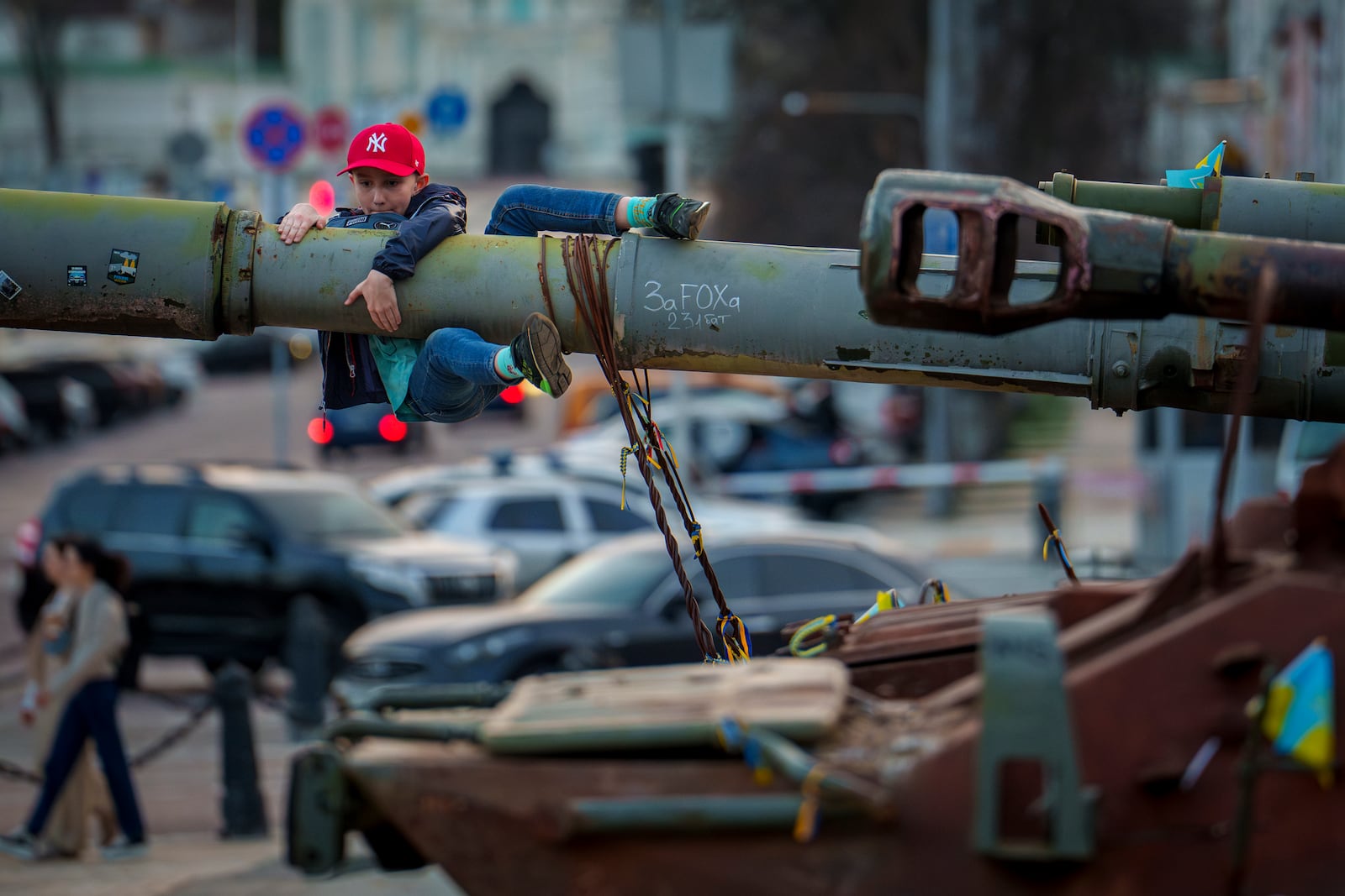 FILE - A boy holds on to the barrel of a tank, part of a display of destroyed Russian military equipment, in Kyiv, Ukraine, Sunday, March 31, 2024. (AP Photo/Vadim Ghirda, File)