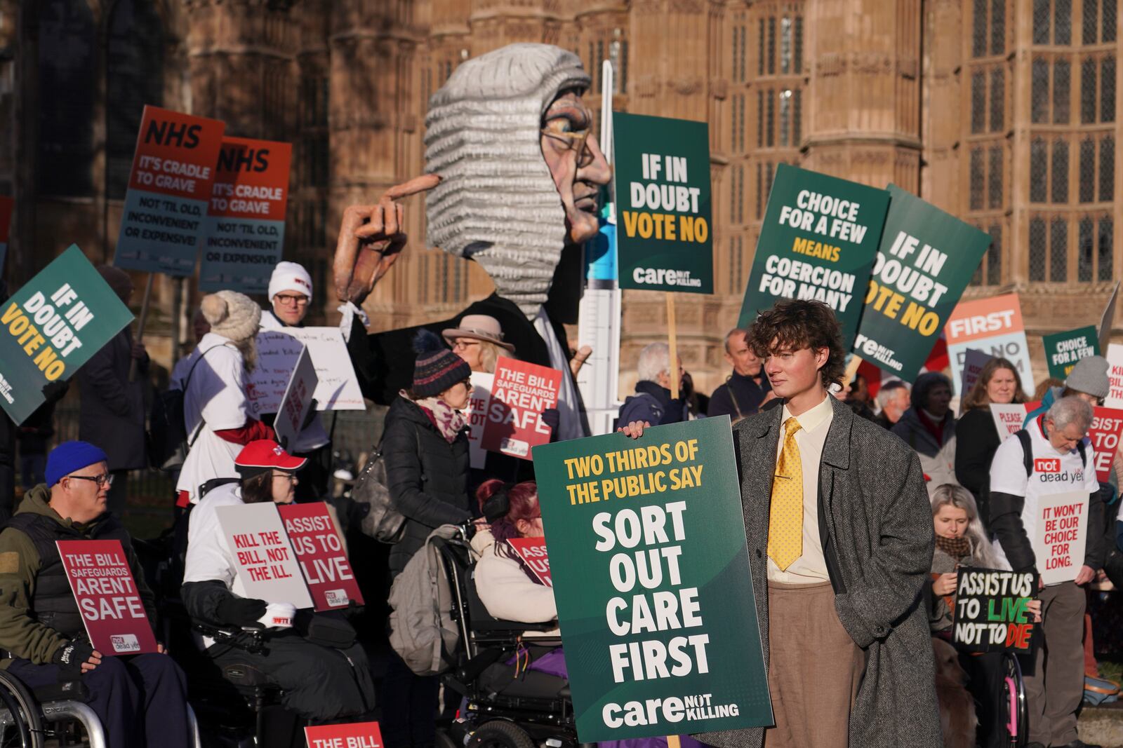 Protesters show posters and placards in front of Parliament in London, Friday, Nov. 29, 2024 as British lawmakers started a historic debate on a proposed to help terminally ill adults end their lives in England and Wales.(AP Photo/Alberto Pezzali)