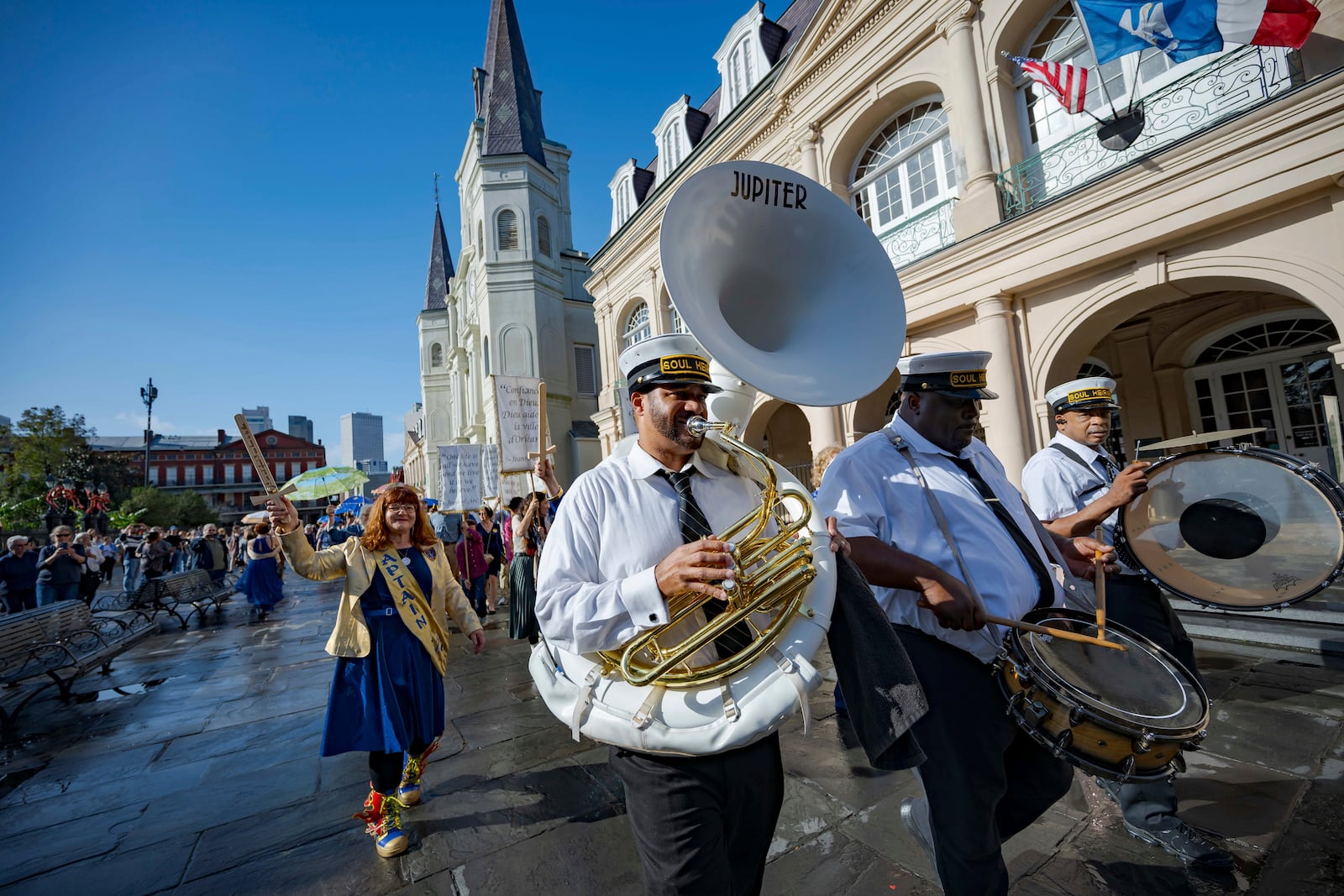 A procession of Krewe de Jeanne d'Arc represented by co-captain Antoinette de Alteriis, left, and the Soul Heirs Brass Band leaves St. Louis Cathedral in New Orleans, Sunday, Jan. 5, 2025, after a mass honoring the victims of the New Year's Day deadly truck attack and shooting not far from the cathedral in the French Quarter. (AP Photo/Matthew Hinton)