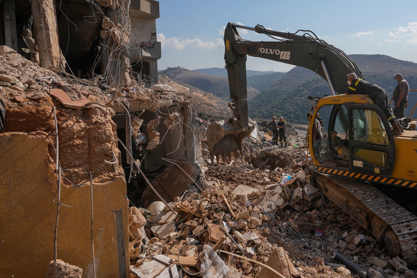 Rescue workers use an excavator to remove the rubble of a destroyed building hit in an Israeli airstrike on Tuesday night, as they search for victims in Barja, Lebanon, Wednesday, Nov. 6, 2024. (AP Photo/Hassan Ammar)