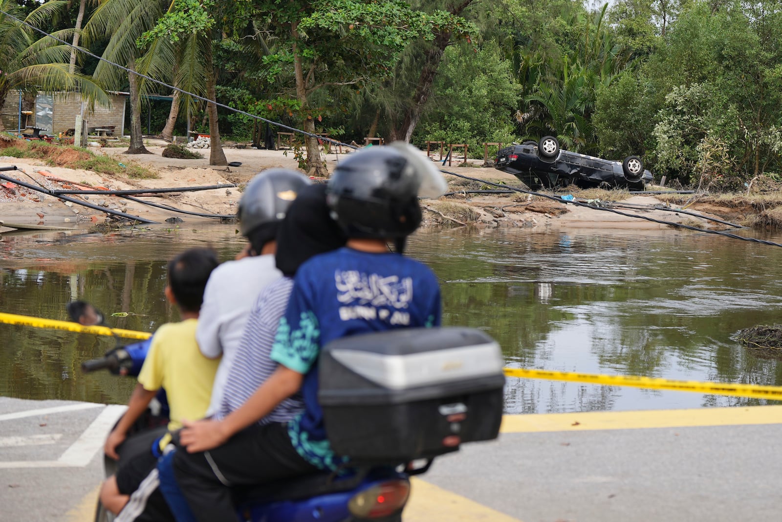 Motorists survey the damage caused by a flood in Tumpat, on the outskirts of Kota Bahru in Kelantan state on the east coast of Malaysia, Tuesday, Dec. 3, 2024. (AP Photo/Vincent Thian)