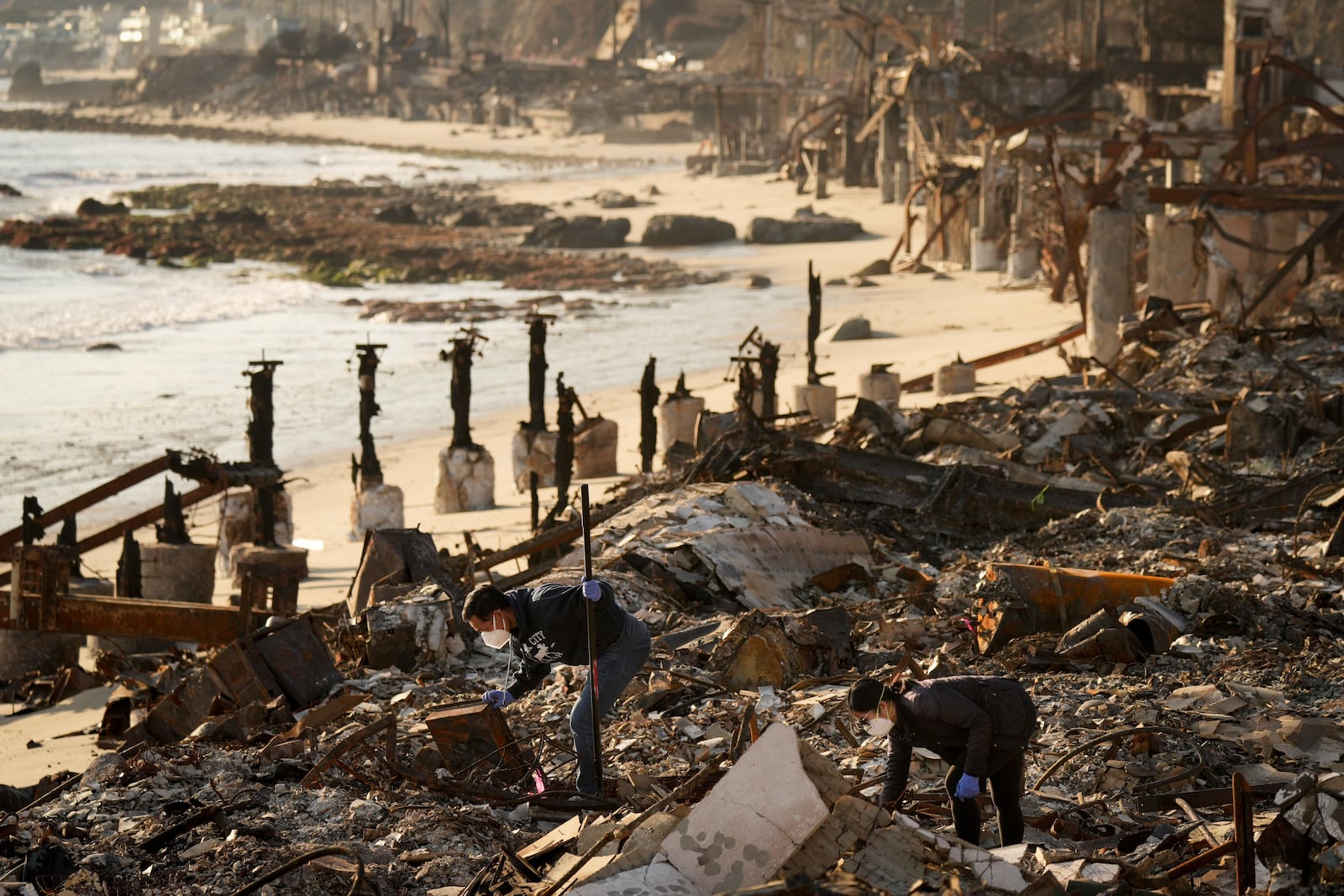 Tony Lai, left, looks through the remains of his fire-ravaged beachfront property with his wife Everlyn in the aftermath of the Palisades Fire Tuesday, Jan. 28, 2025 in Malibu, Calif. (AP Photo/Jae C. Hong)