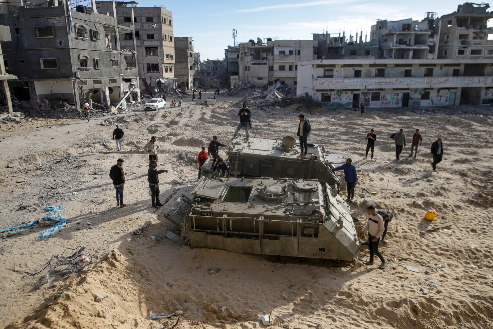 Palestinian youth walk atop the remains of military armored vehicles left behind after the Israeli air and ground offensive against Hamas, in Rafah, southern Gaza Strip, Monday, Jan. 20, 2025. (AP Photo/Jehad Alshrafi)