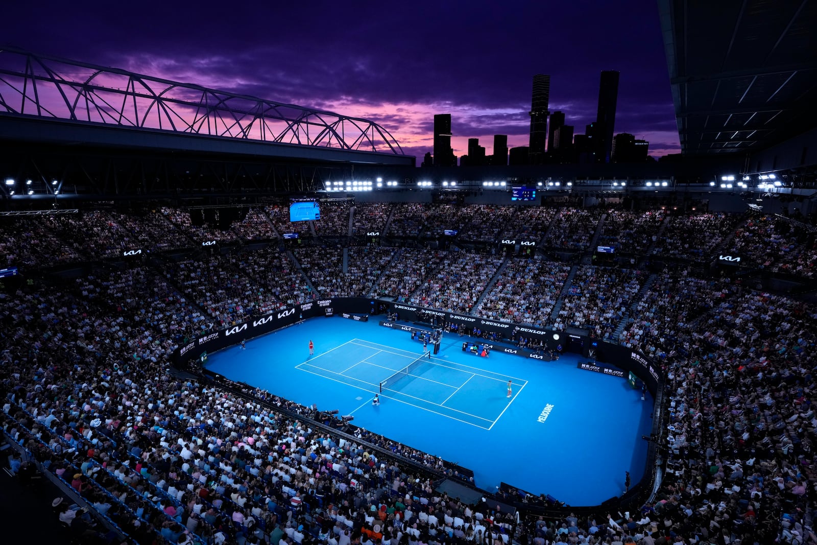 FILE - Aryna Sabalenka of Belarus, left, and Zheng Qinwen of China play as the sun sets during the women's singles final at the Australian Open tennis championships at Melbourne Park, Melbourne, Australia, Jan. 27, 2024. (AP Photo/Louise Delmotte, File)