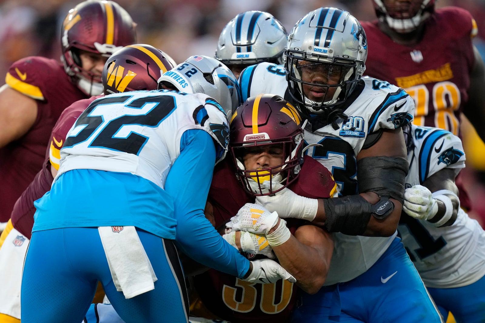 Washington Commanders running back Austin Ekeler (30) is tackled by Carolina Panthers linebacker DJ Johnson (52) and defensive end LaBryan Ray (93) during the second half of an NFL football game, Sunday, Oct. 20, 2024, in Landover, Md. (AP Photo/Stephanie Scarbrough)