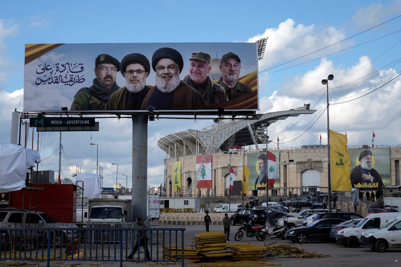 People walk past a billboard with pictures of the late Lebanon's Hezbollah leader Sayyed Hassan Nasrallah, center, late Lebanon's Hezbollah leader Sayyed Hashem Safieddine, second left, Hezbollah top commander Fouad Shukur, left, Hezbollah senior commander Ali Karaki, second right, and Hezbollah commander Ibrahim Akil, right, displayed on Beirut airport highway, Lebanon, Friday, Feb. 21, 2025. (AP Photo/Bilal Hussein)