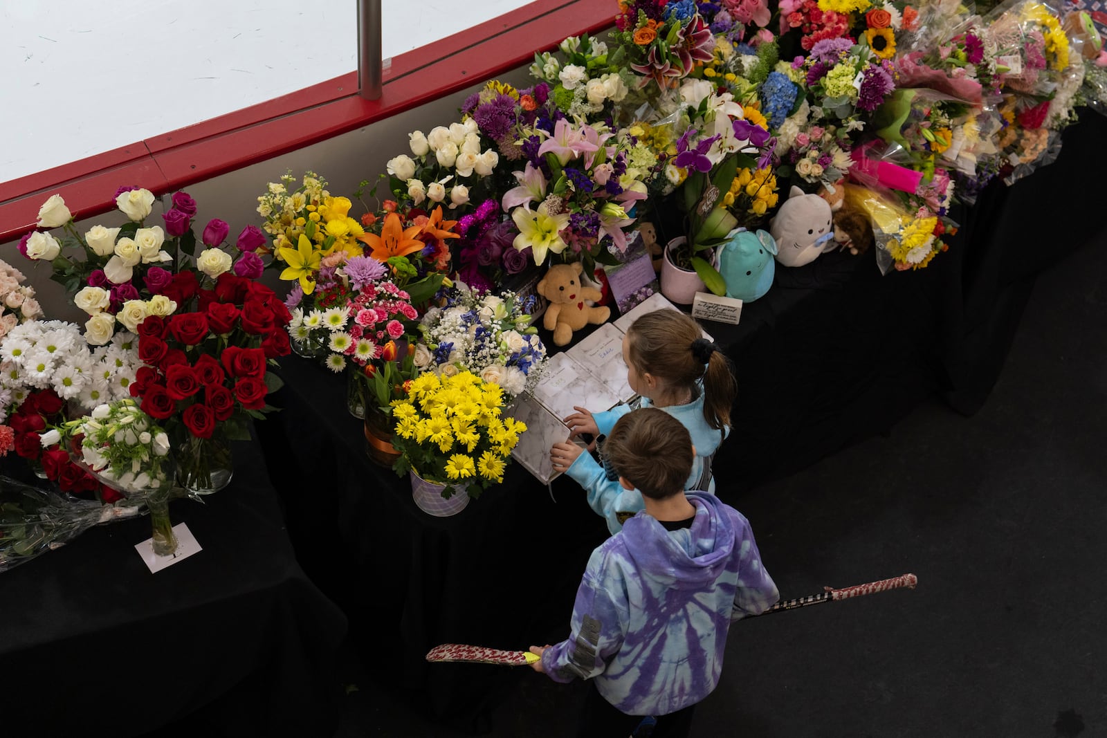 Young skates visit a memorial along the boards at MedStar Capitals Iceplex Sunday, Feb. 2, 2025, in Arlington, Va., for the figure skaters who were among the 67 victims of a mid-air collision between an Army helicopter and an American Airlines flight from Kansas. (AP Photo/Carolyn Kaster)