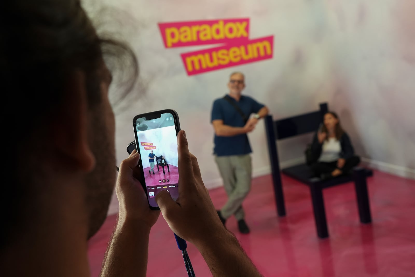 Argentine tourists Lilia, right, and Jose Auad pose for a picture creating an optical illusion distorting their size, at Paradox Museum Miami, Tuesday, Jan. 28, 2025, in Miami. (AP Photo/Rebecca Blackwell)