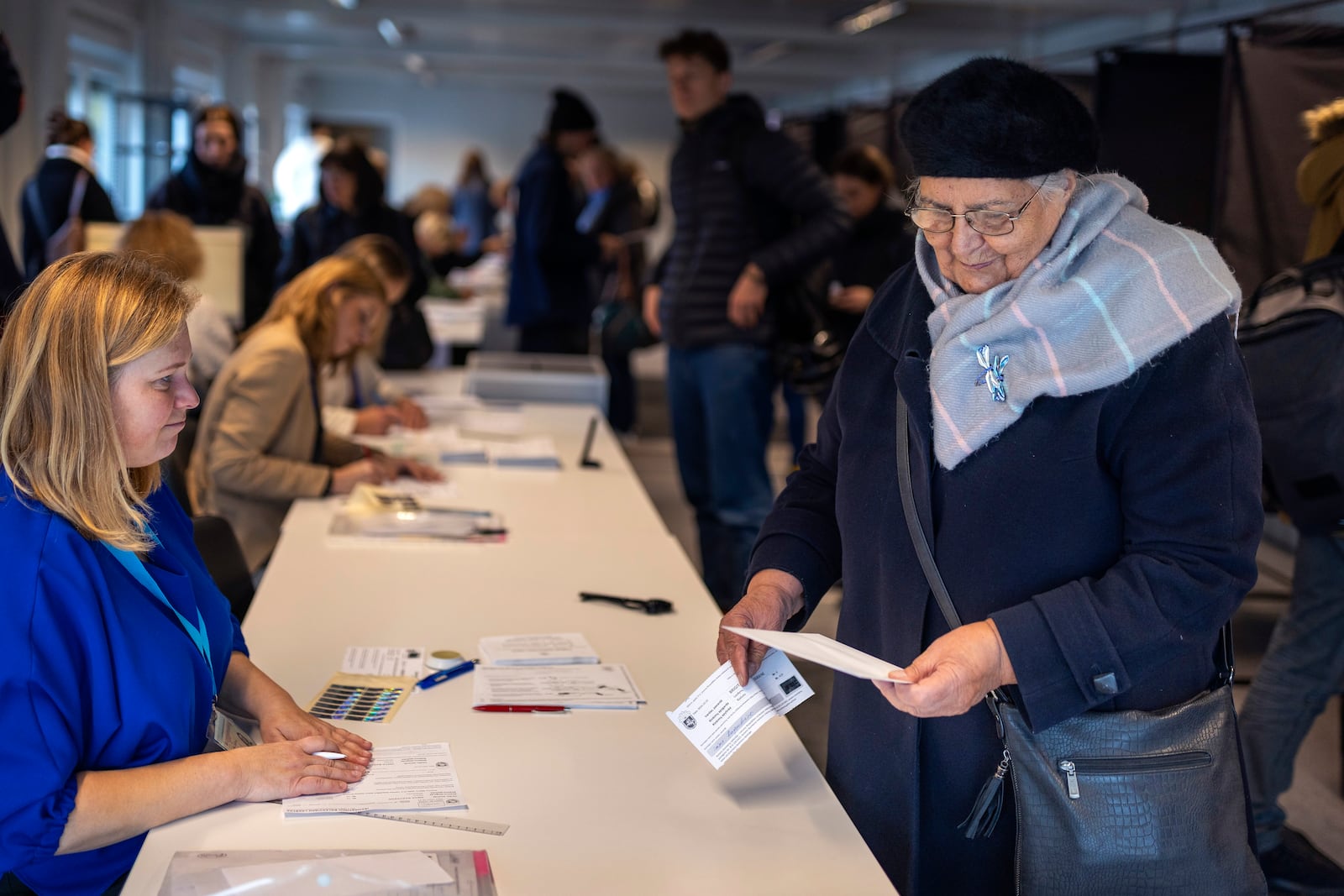 A woman reads the ballot paper at a polling station during the advance voting in the second round of a parliamentary election in Vilnius, Lithuania, Tuesday, Oct. 22, 2024. (AP Photo/Mindaugas Kulbis)