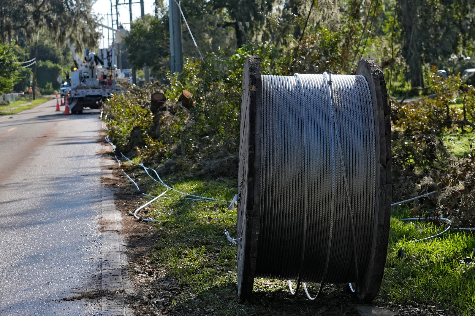 A large spool of electrical wire sits among Hurricane Milton debris as linemen from Pike Corporation, of North Carolina, fix wires Sunday, Oct. 13, 2024, in Valrico, Fla. (AP Photo/Chris O'Meara)