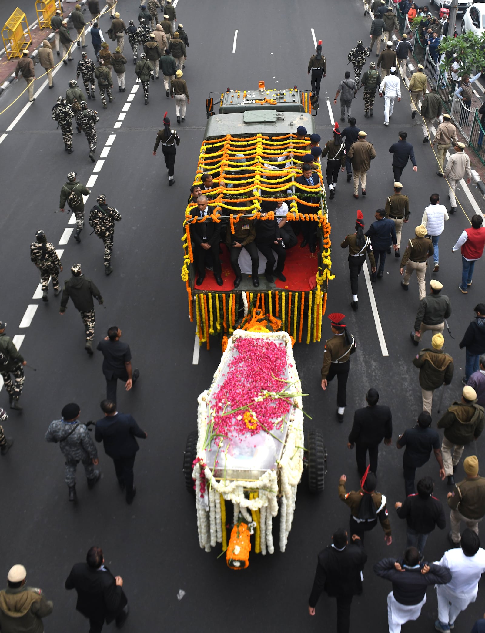 Security officials and others walk with the hearse carrying the body of former Indian Prime Minister Manmohan Singh towards the cremation site in New Delhi, India, Saturday, Dec. 28, 2024. (AP Photo)