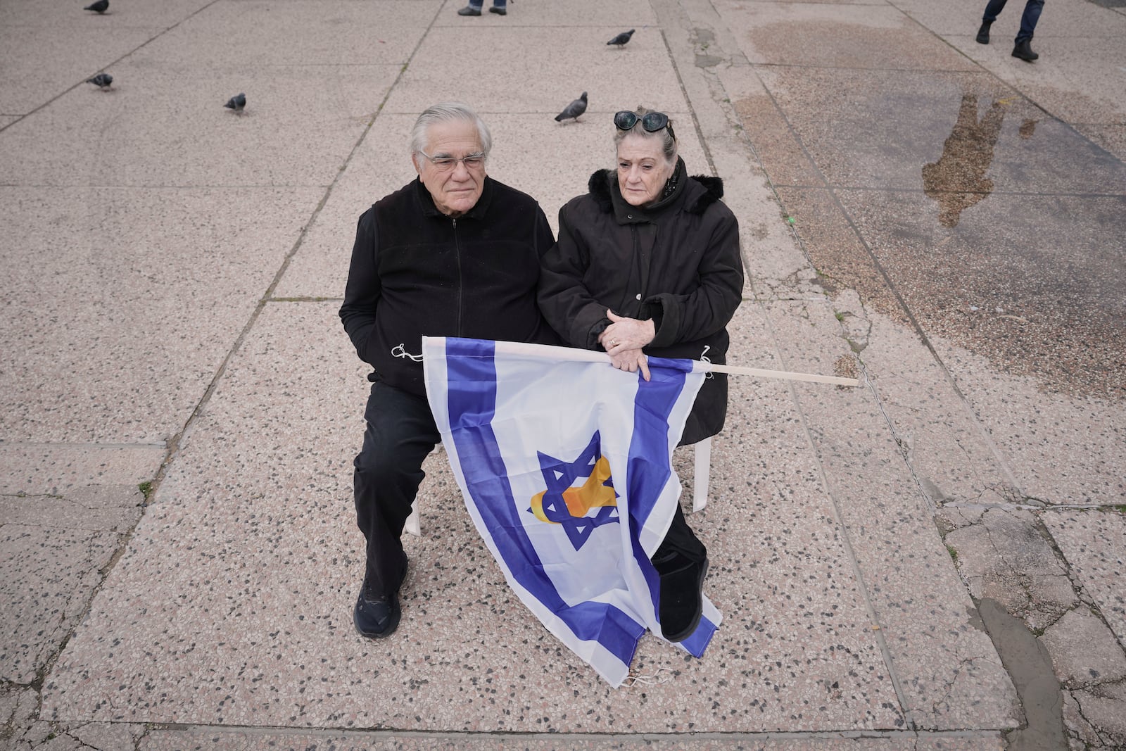 Israelis Shoshi and Dov Peleg wait in the Hostages square for the release of the Israelis kidnapped by Hamas in Gaza, as they begin to gather in Tel Aviv, Israel on Saturday, Feb. 8, 2025. (AP Photo/Oded Balilty)