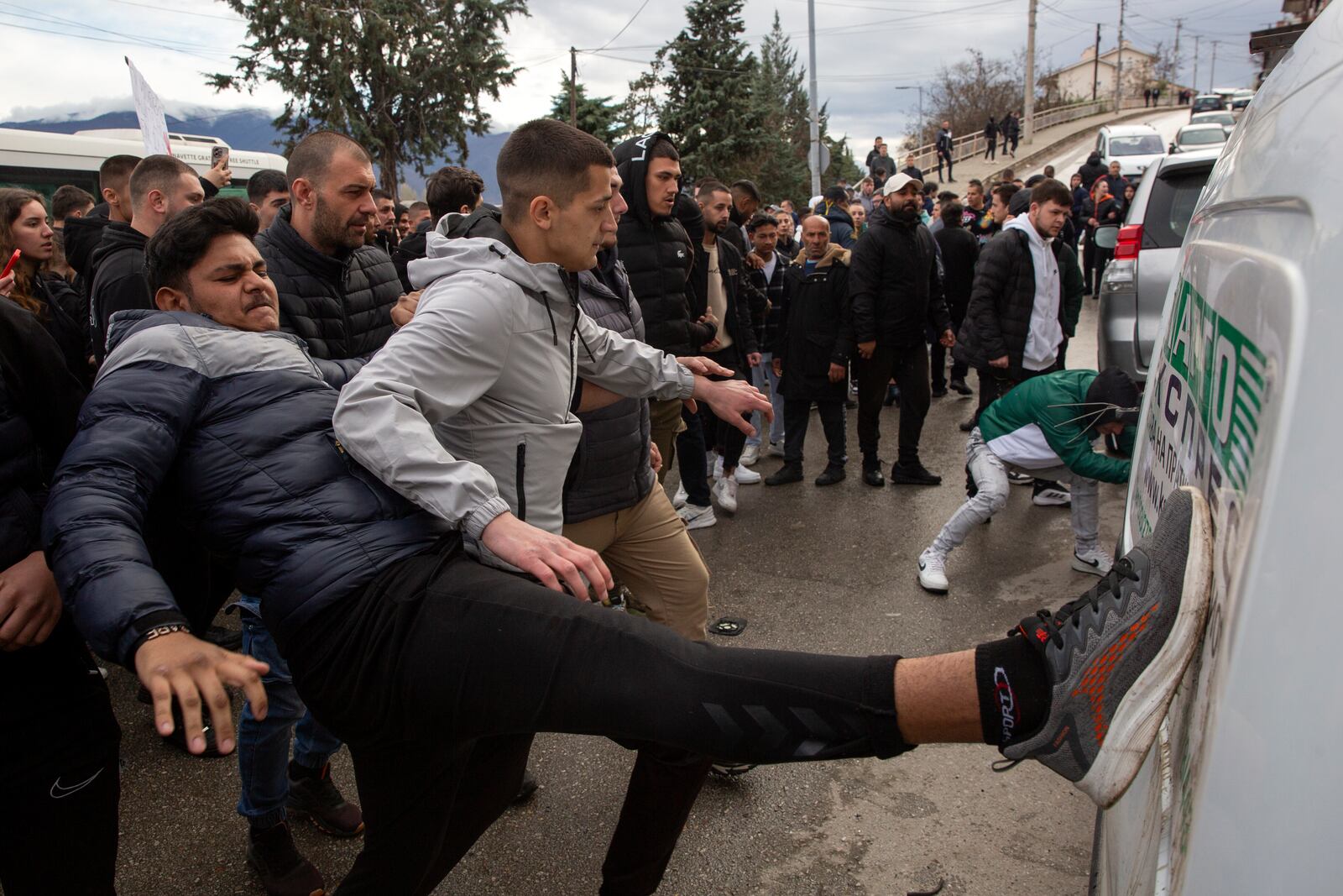 People hit a car on its side while protesting near the home of the owner of a nightclub that was the scene of a massive fire, after a vigil for the victims in the town of Kocani, North Macedonia, Monday, March 17, 2025. (AP Photo/Visar Kryeziu)