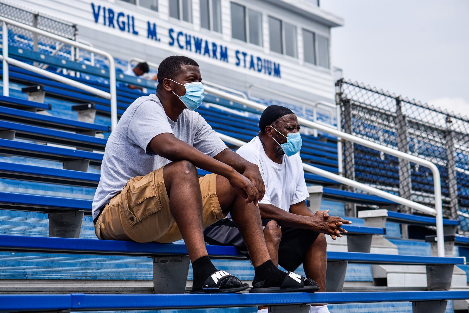 Deaeris Givens, left, and Adell Givens wear masks as they watch the Hamilton High School football team practice Wednesday, August 12, 2020 at Virgil M. Schwarm Stadium in Hamilton. NICK GRAHAM / STAFF