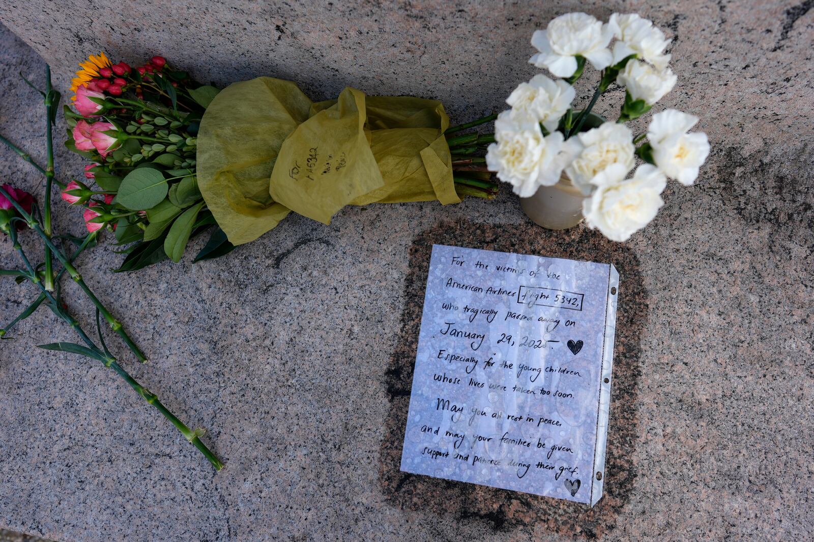 Flowers and a letter in memorial to the victims of a mid-air collision of an American Airlines jet and a Black Hawk helicopter near the Potomac river are pictured at the Titanic Memorial, Saturday, Feb. 1, 2025, in Washington. (AP Photo/Carolyn Kaster)