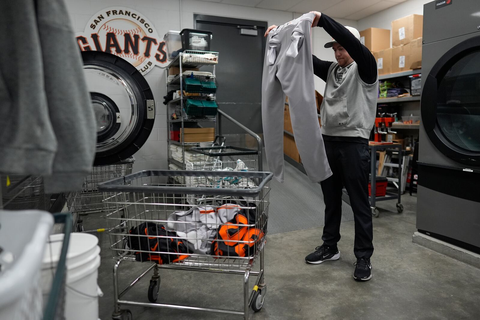 San Francisco Giants clubhouse attendant Riley Halpin inspects baseball pants for stains and pine tar in the laundry room during baseball spring training at the team's facility, Monday, Feb. 17, 2025, in Scottsdale, Ariz. (AP Photo/Carolyn Kaster)