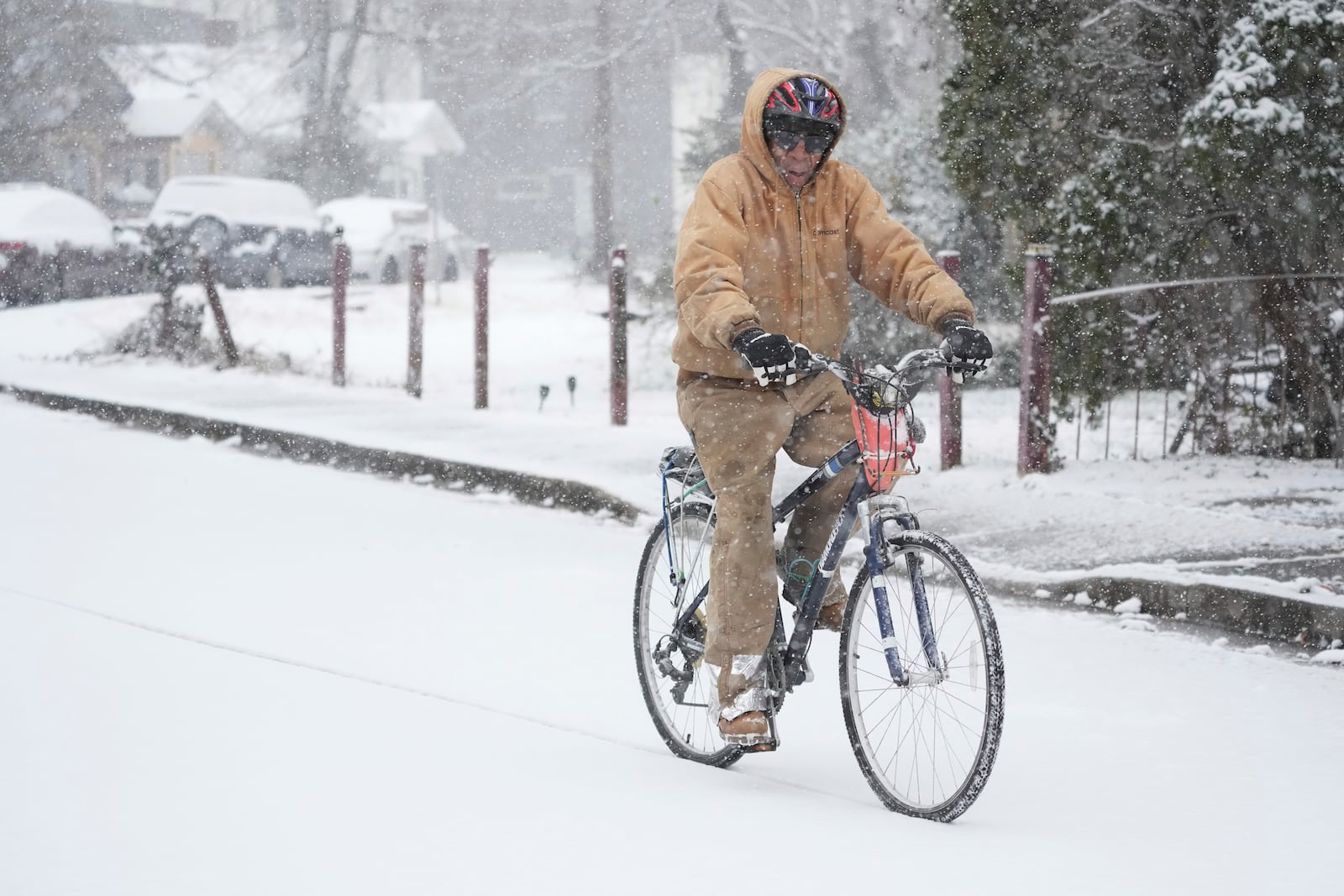 Jesse Thompson rides his bicycle in the snow Friday, Jan 10, 2025, in Nashville, Tenn. (AP Photo/George Walker IV)