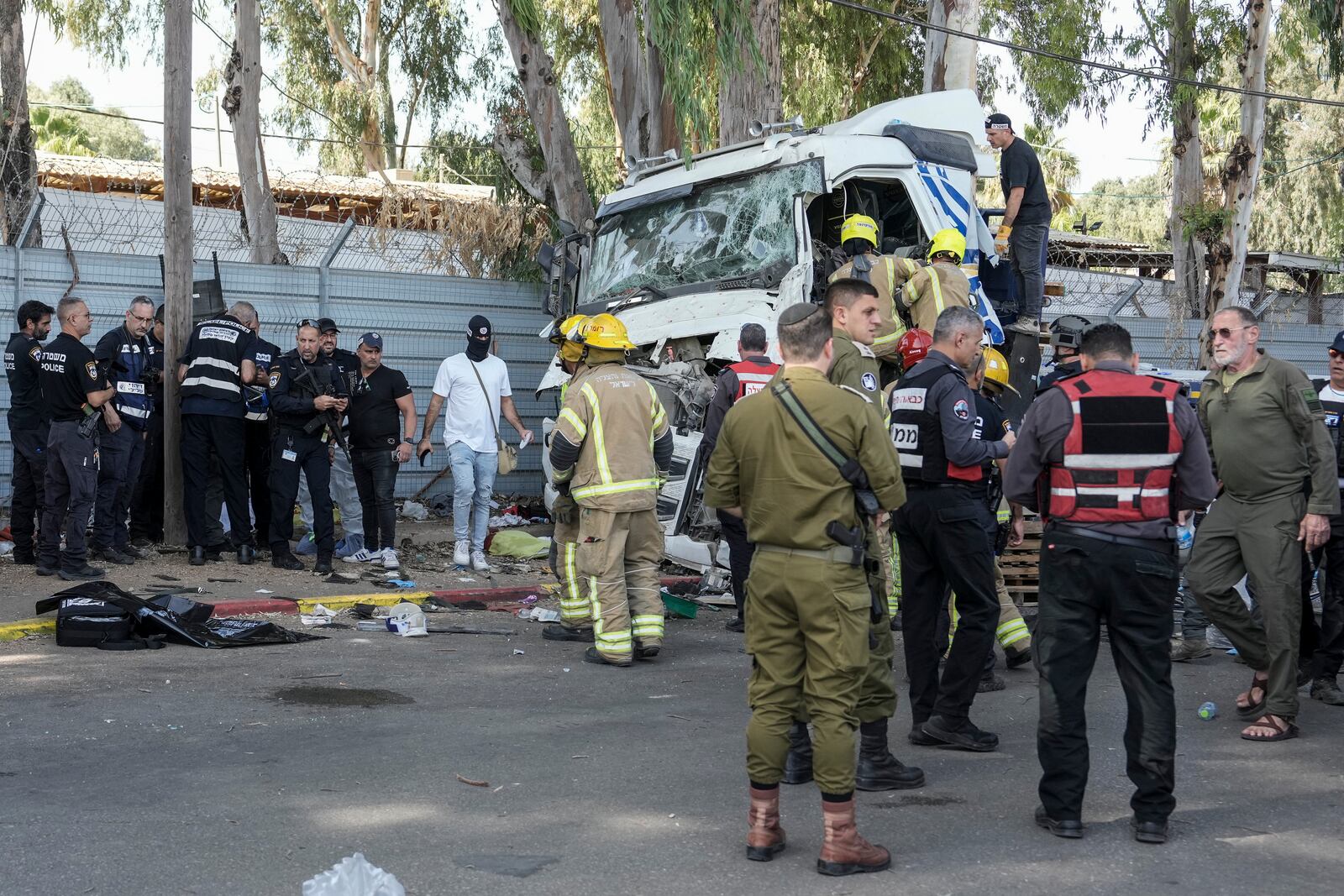 Israeli police and rescue workers climb on a truck to inspect the body of a driver that rammed into a bus stop near the headquarters of Israel's Mossad spy agency, wounding dozens of people, according to Israel's Magen David Adom rescue service in Tel Aviv, Israel, Sunday, Oct. 27, 2024. (AP Photo/Oded Balilty)