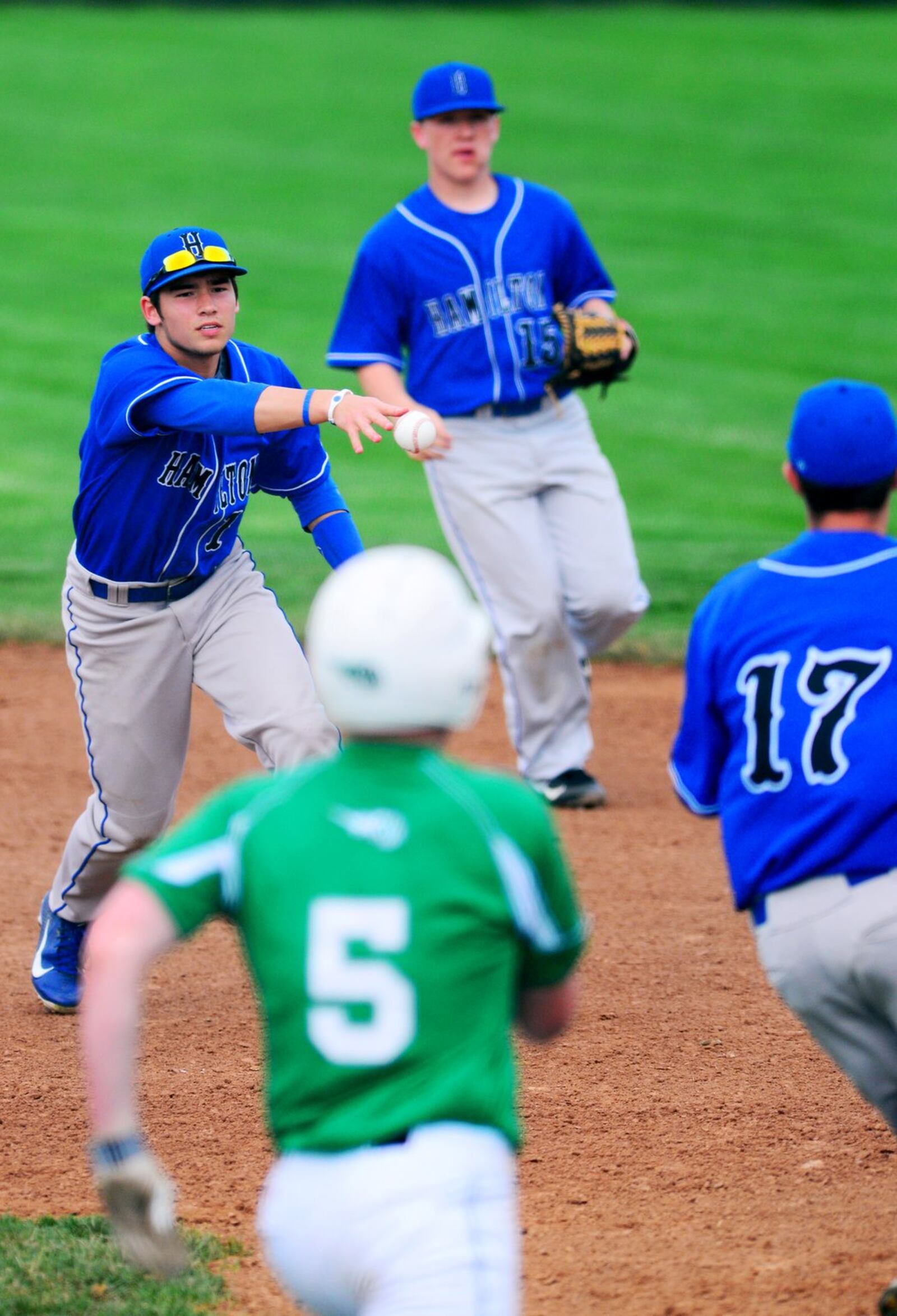 Hamilton first basemen John Heckman flips the ball to pitcher Jake Zeek after fielding a ground ball hit to first in a 13-2 Big Blue loss at Mason on April 18, 2013. JOURNAL-NEWS FILE PHOTO