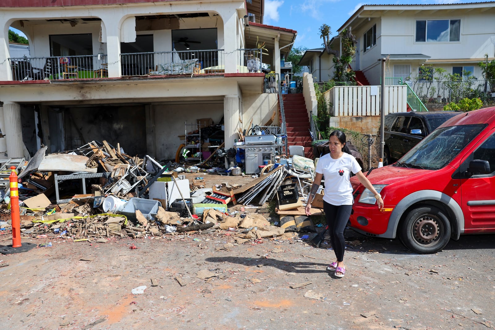 A woman walks in front of the home where a New Year's Eve fireworks explosion killed and injured people, Wednesday, Jan. 1, 2025, in Honolulu. (AP Photo/Marco Garcia)