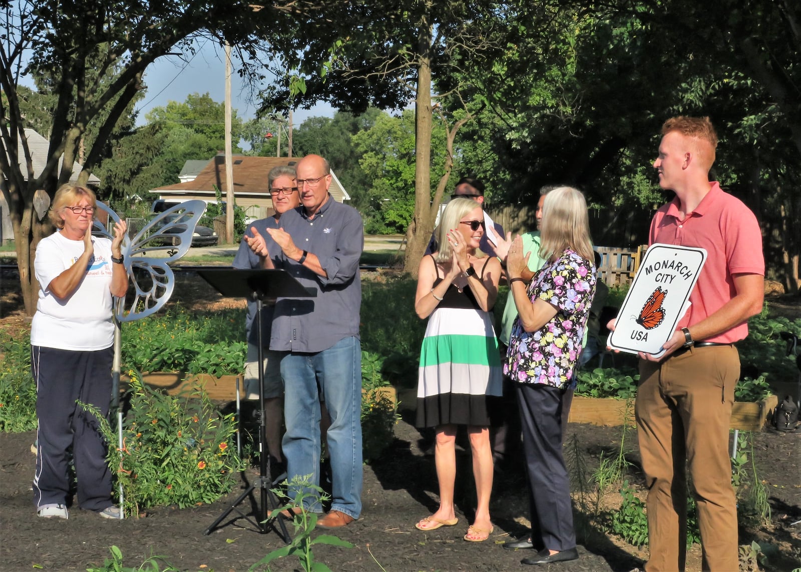 City officials, park creator Alfred Hall (immediately left of the butterfly sculpture, standing behind Mayor Pat Moeller), and neighbors gathered to celebrate the opening of a pollinator park in Hamilton. PROVIDED