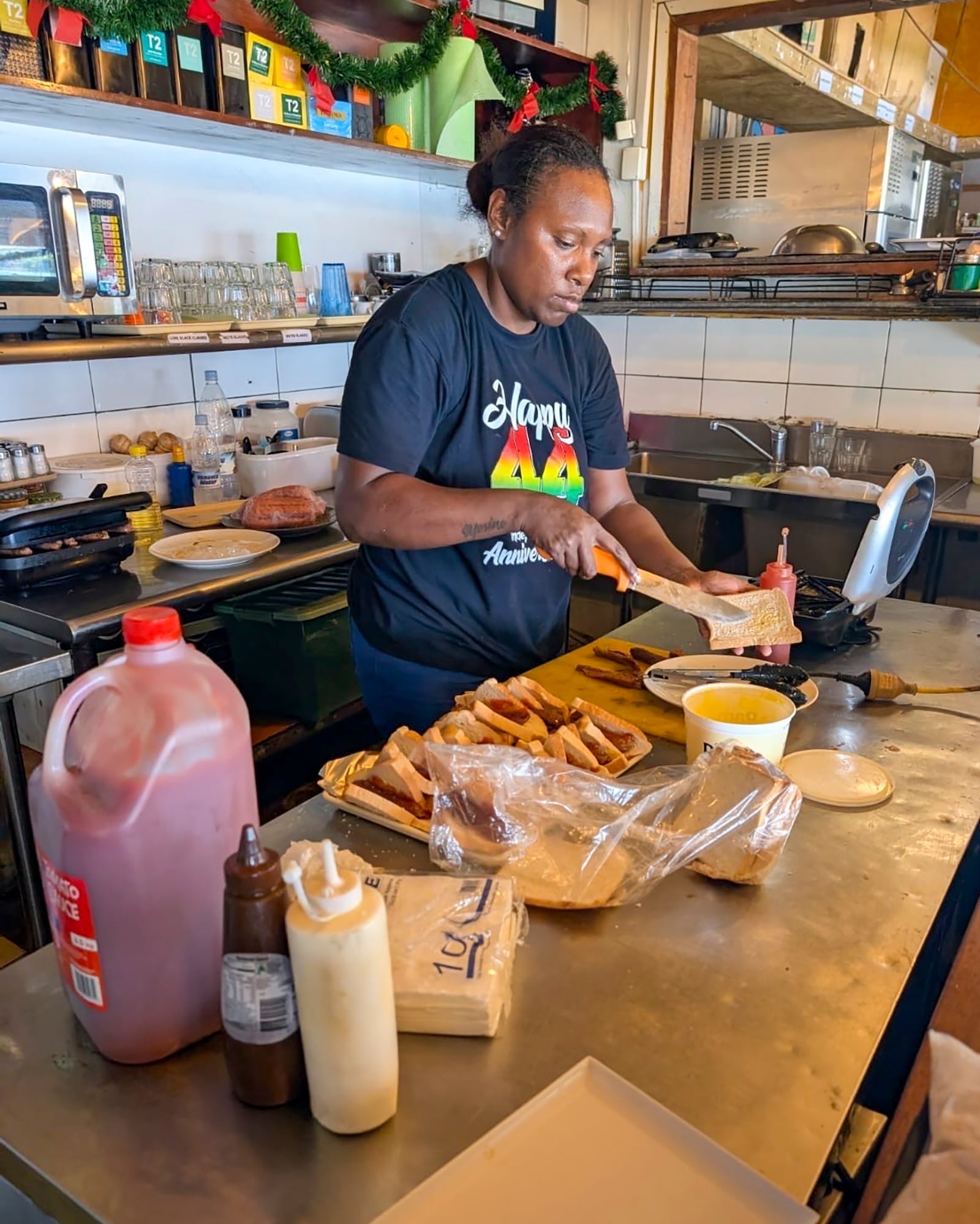 Josephine Taut makes sausages for emergency workers at Nambawan Cafe in Port Vila, Thursday, Dec. 19, 2024, following a strong earthquake that struck off the coast of Vanuatu in the South Pacific Ocean, Tuesday, Dec. 17. (Ivan Oswald via AP)