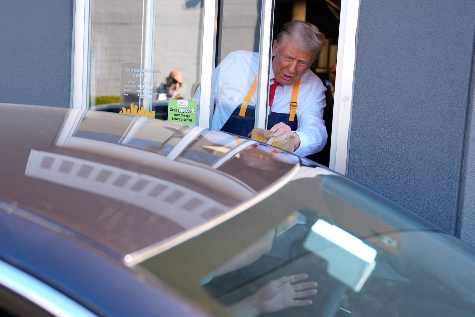 Republican presidential nominee former President Donald Trump hands an order to a customer at a drive-thru window during a campaign stop at a McDonald's, Sunday, Oct. 20, 2024, in Feasterville-Trevose, Pa. (AP Photo/Evan Vucci)