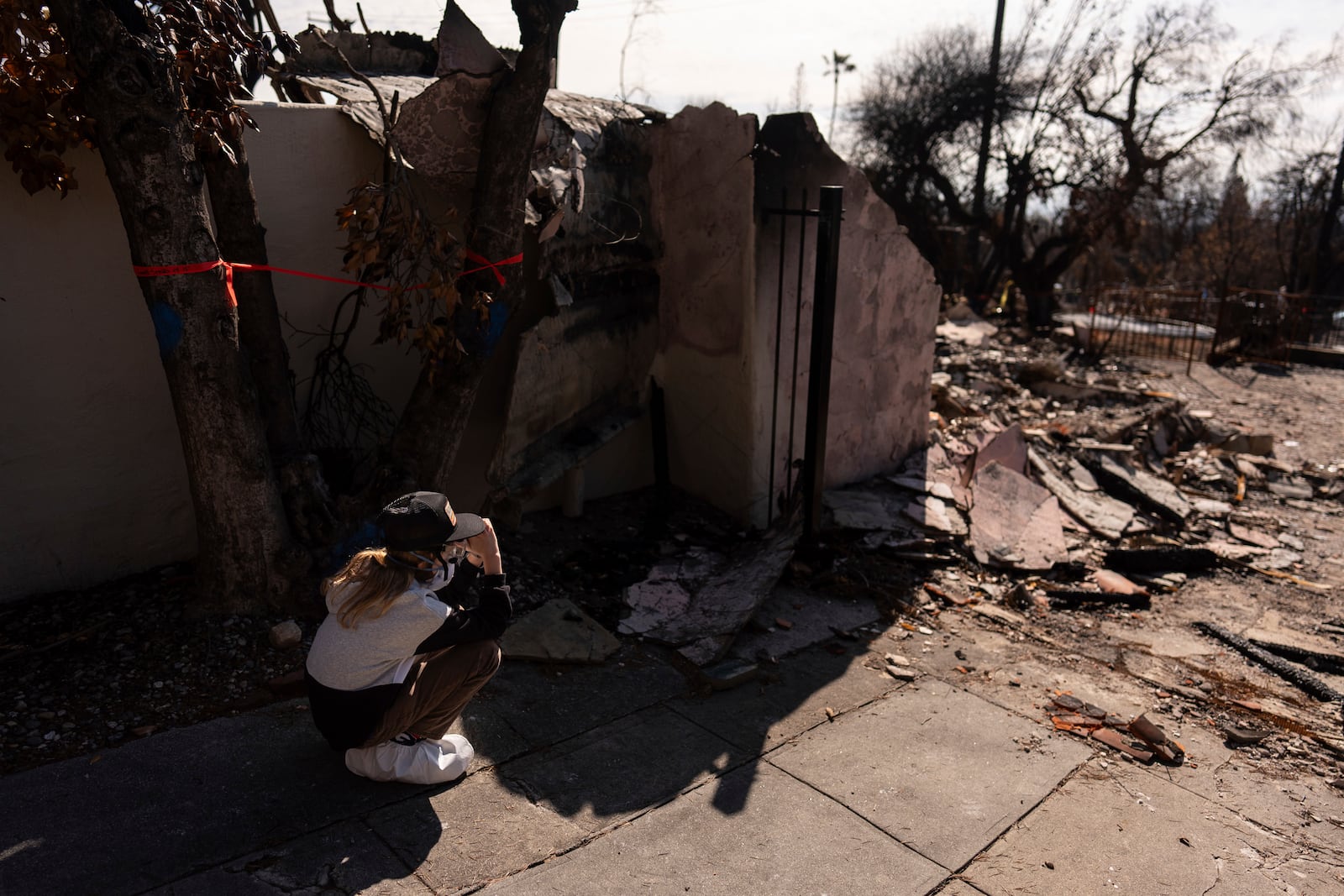 Eaton Fire evacuee Ceiba Phillips, 11, is overwhelmed with emotion as he visits his best friend's home, which was devastated by the fire, across the street from his own in Altadena, Calif., Saturday, Feb. 8, 2025. (AP Photo/Jae C. Hong)