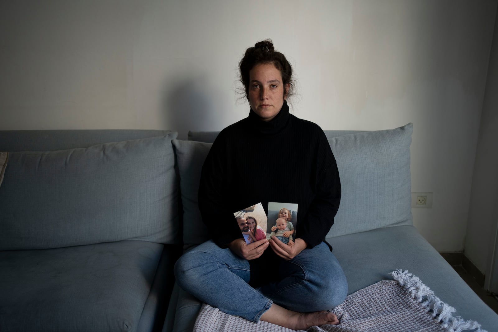 Yifat Zailer shows photos of her cousin, Shiri Bibas, center, her husband Yarden, left, and their sons Ariel, top right, and Kfir, were taken hostage by Hamas militants, as she poses for a portrait at her home in Herziliyya, Israel, on Wednesday, Jan. 15, 2025. (AP Photo/Maya Alleruzzo)