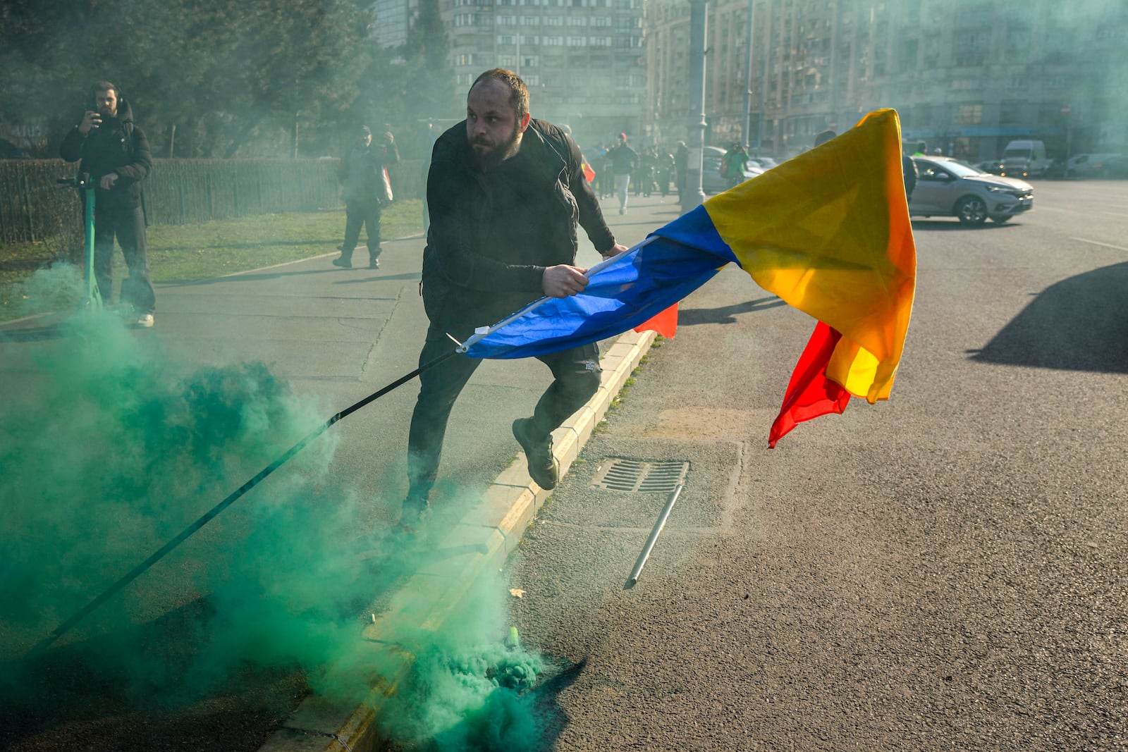 A man holding a Romanian flag runs after breaking through police lines in front of the government headquarters during a protest by supporters of Calin Georgescu, the winner of Romania's first round of presidential election which the Constitutional Court later annulled, in Bucharest, Romania, Monday, Feb. 10, 2025. (AP Photo/Vadim Ghirda)