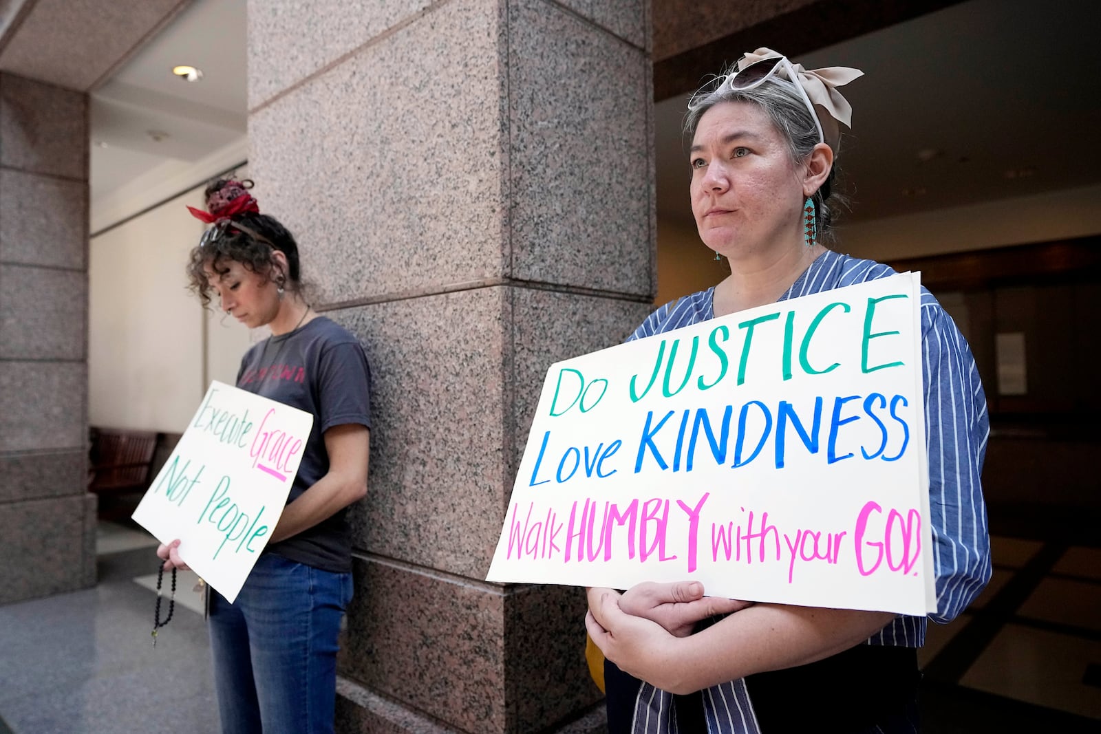 FILE -= Sascha Anderson, right, and Sam McRae, left, hold signs as they stand outside a room where a committee is discussing the case of death row inmate Robert Roberson, Monday, Oct. 21, 2024, in Austin, Texas. (AP Photo/Tony Gutierrez, File)