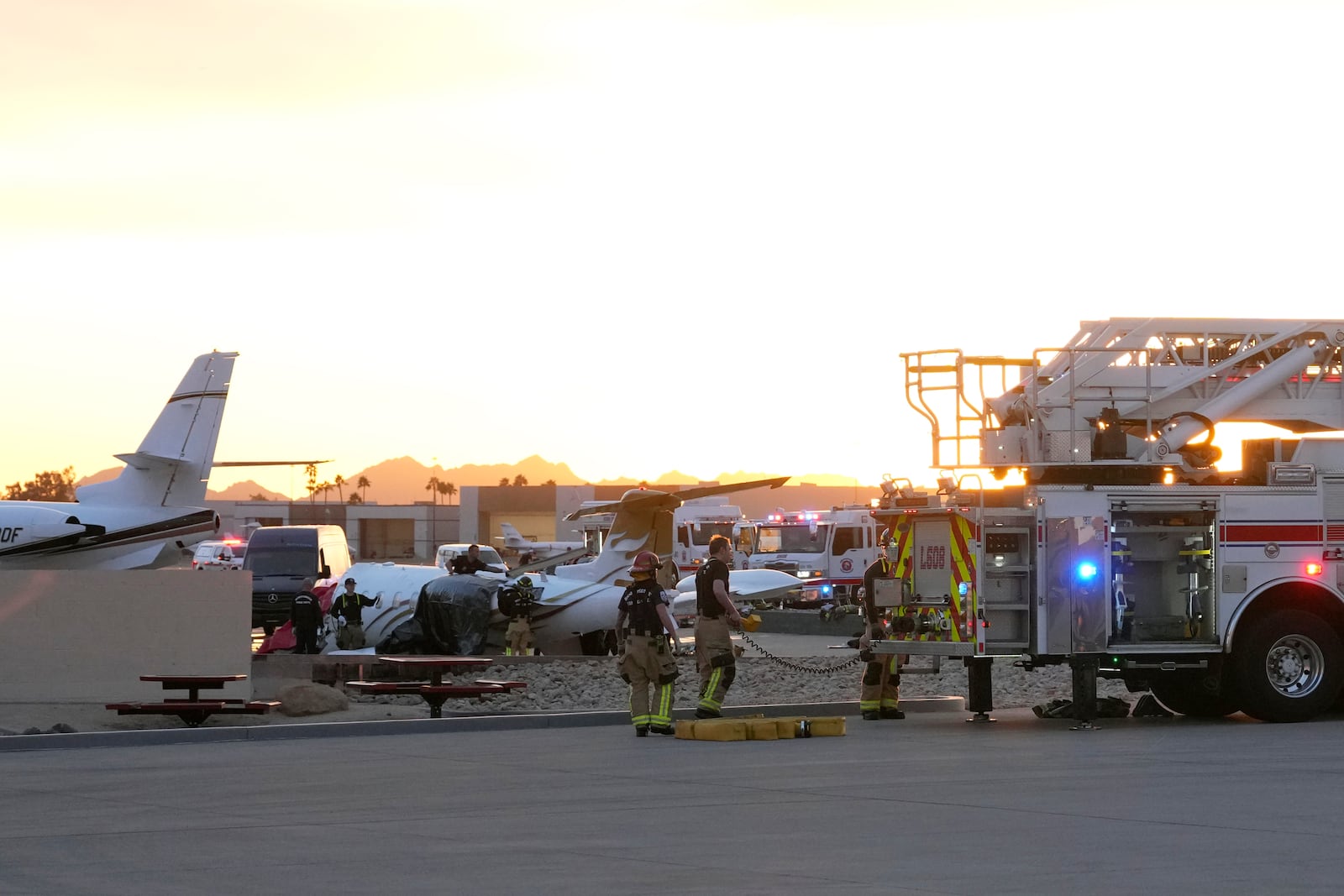 Members of the Scottsdale Fire Department stand near a crashed Learjet at Scottsdale Airport after it collided with a parked plane Monday, Feb. 10, 2025, in Scottsdale, Ariz. (AP Photo/Ross D. Franklin)