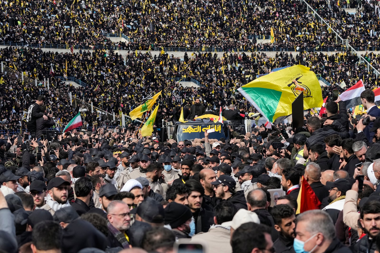 A trailer carrying the coffins containing the bodies of Hezbollah's former leader Hassan Nasrallah and his cousin and successor Hashem Safieddine drives through the crowd at the beginning of a funeral procession in the Sports City Stadium in Beirut, Lebanon, Sunday, Feb. 23, 2025. (AP Photo/Hussein Malla)