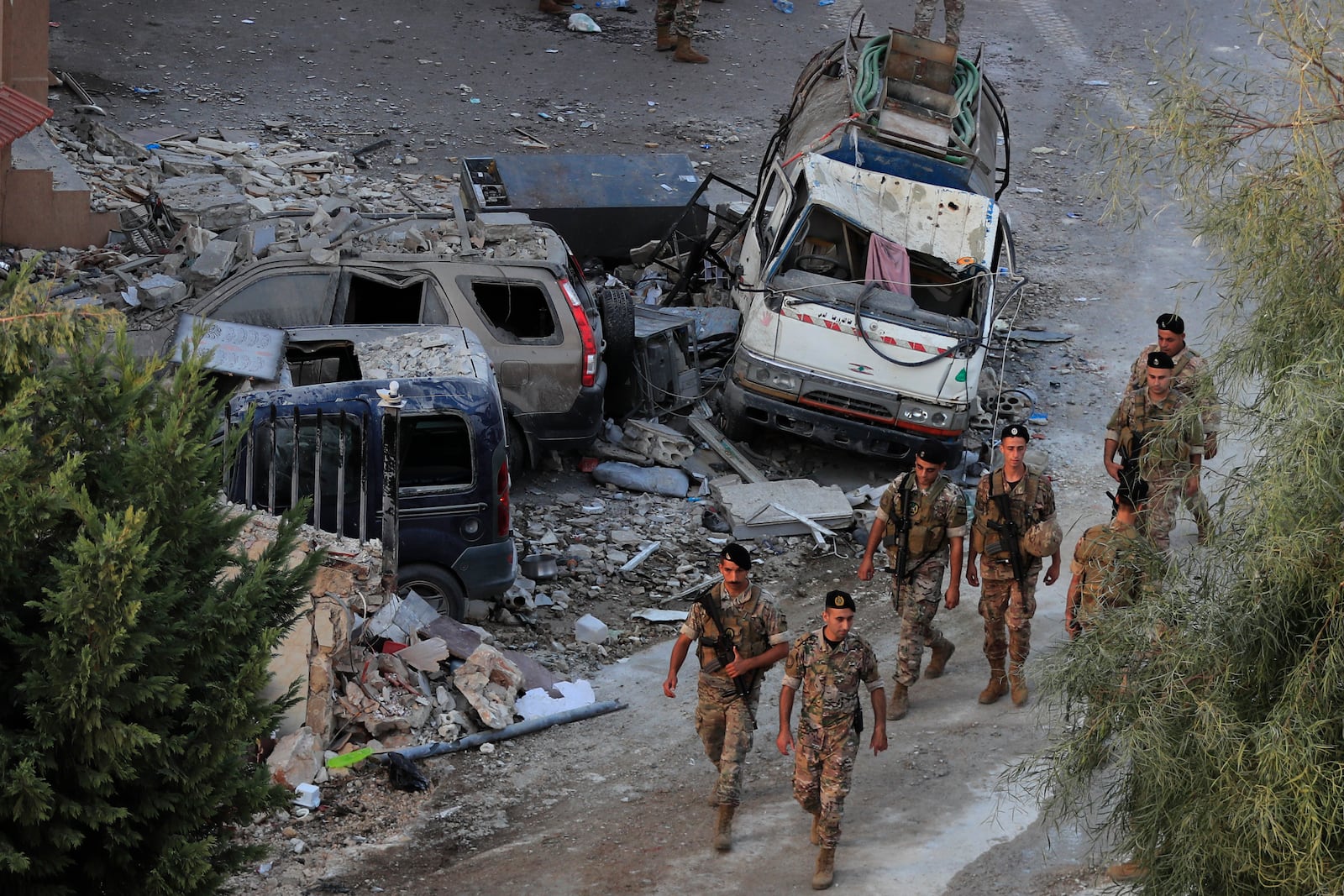 Lebanese army soldiers walk by destroyed cars at the site where an Israeli airstrike hit a building, in Barja village, south of Beirut, Lebanon, Saturday, Oct. 12, 2024. (AP Photo/Mohammed Zaatari)