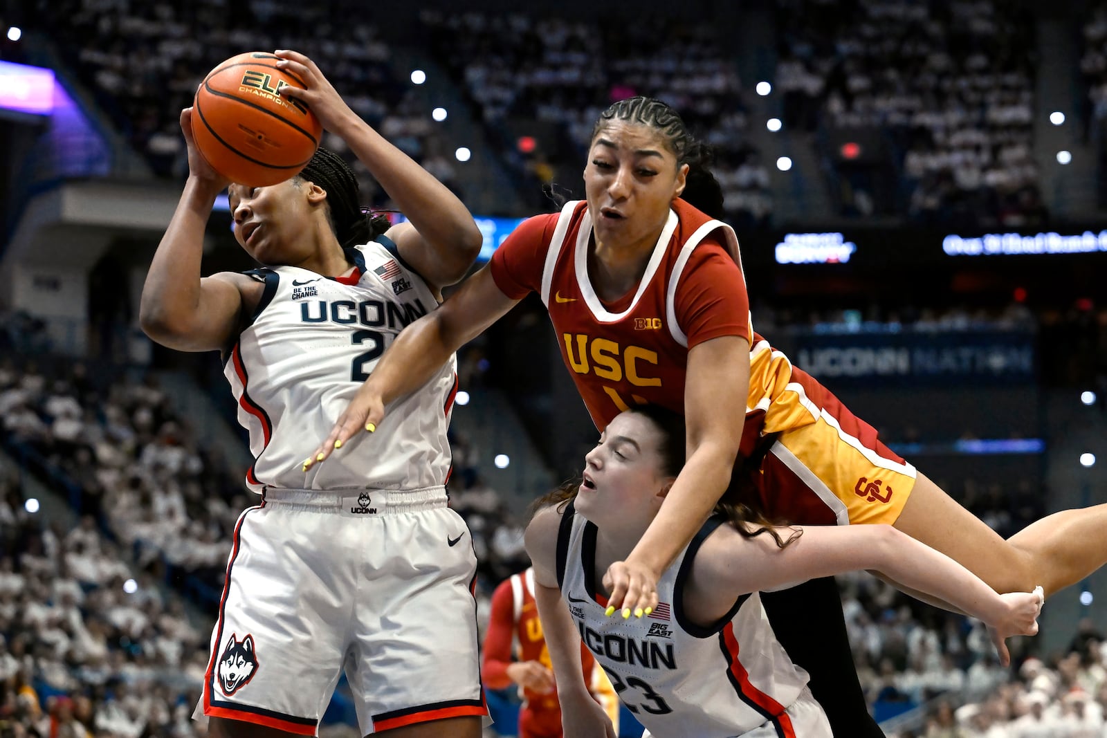 UConn forward Sarah Strong, left, pulls down a rebound as Southern California guard Kennedy Smith and UConn guard Morgan Cheli, bottom right, defend in the first half of an NCAA college basketball game, Saturday, Dec. 21, 2024, in Hartford, Conn. (AP Photo/Jessica Hill)