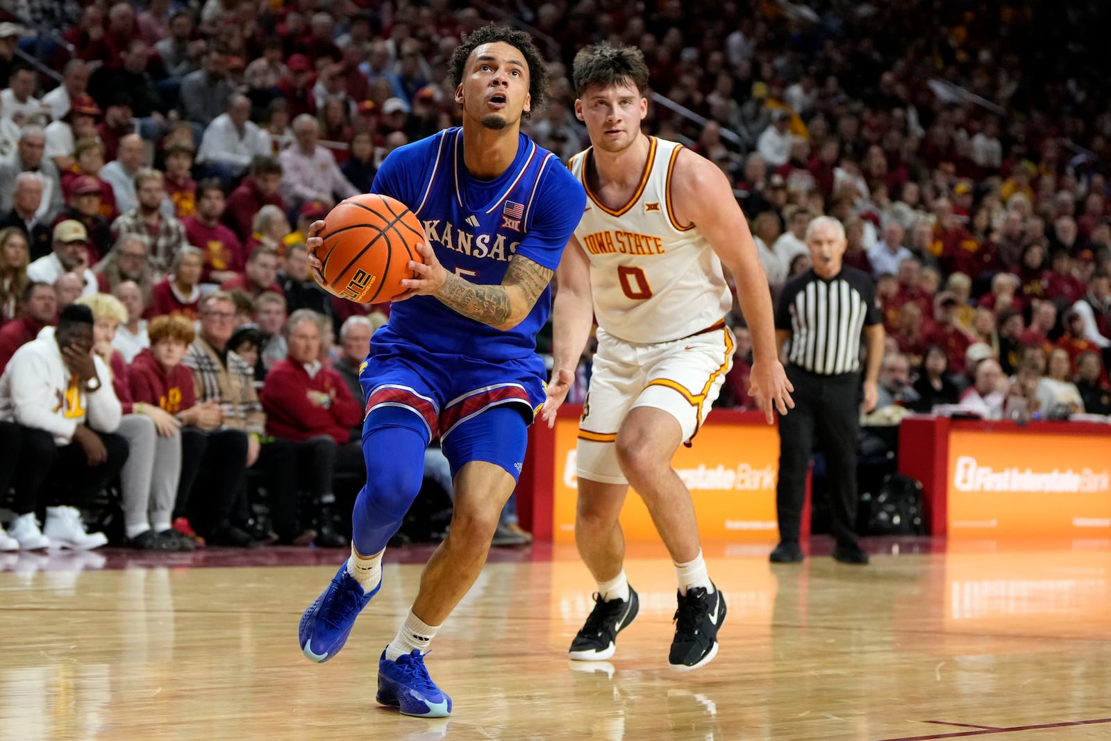 Kansas guard Zeke Mayo (5) drives to the basket past Iowa State guard Nate Heise (0) during the first half of an NCAA college basketball game, Wednesday, Jan. 15, 2025, in Ames, Iowa. (AP Photo/Charlie Neibergall)