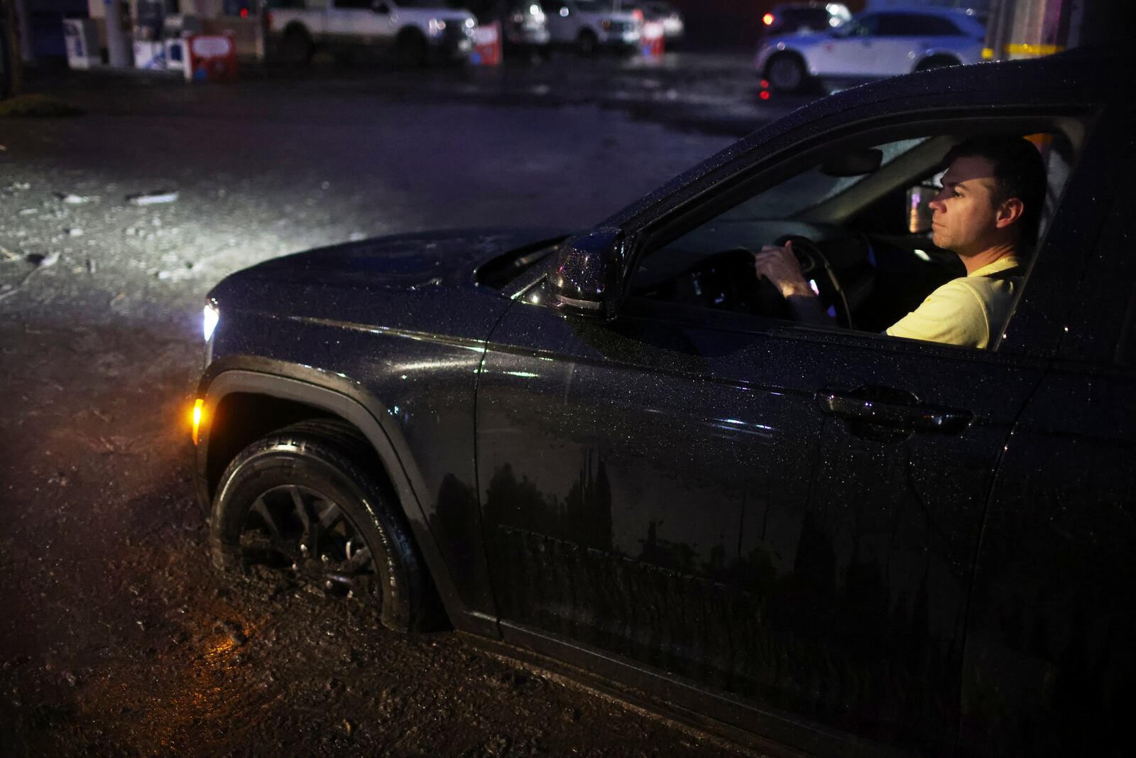 A motorist drives through a mud-covered road in the Palisades Fire zone during a storm Thursday, Feb. 13, 2025, in the Pacific Palisades neighborhood of Los Angeles. (AP Photo/Ethan Swope)