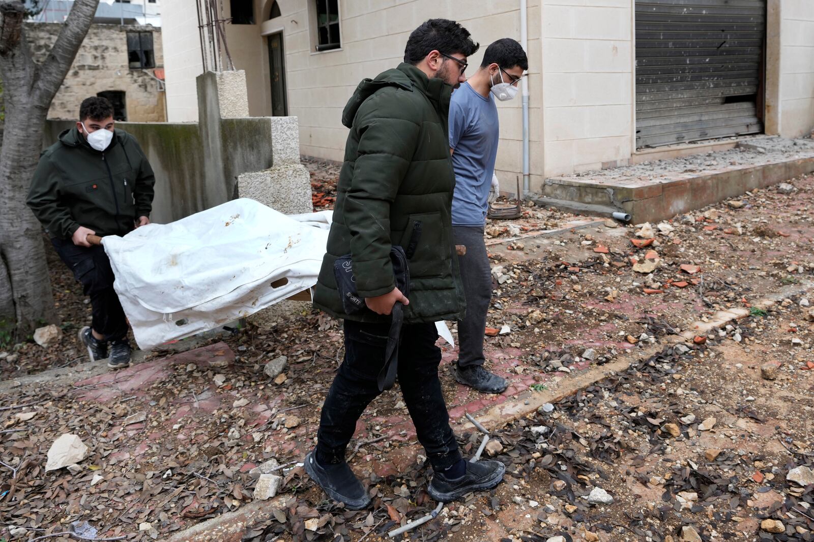 Lebanese men carry a dead body retrieved from under the rubble of a destroyed house in Ainata village, southern Lebanon, following a ceasefire between Israel and Hezbollah that went into effect on Wednesday, Nov. 27, 2024. (AP Photo/Hussein Malla)