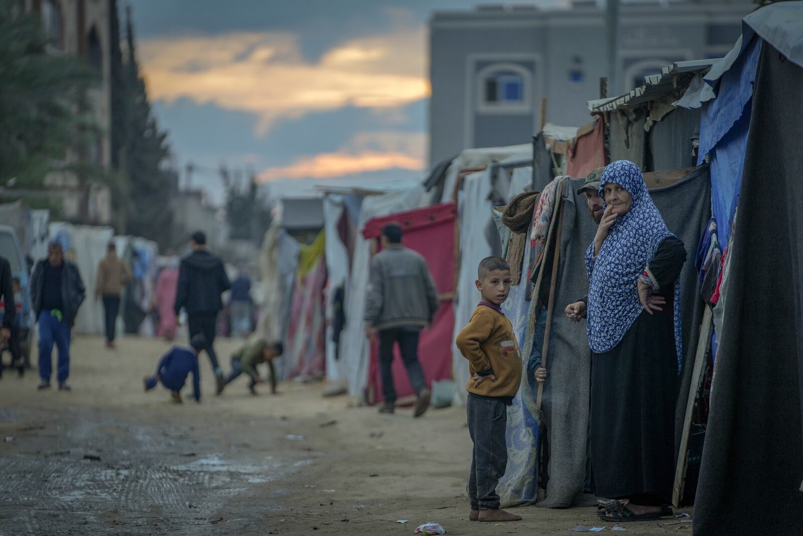 Palestinians stand outside their tents at a camp for displaced people in Deir al-Balah, Gaza Strip, Thursday, Dec. 12, 2024. (AP Photo/Abdel Kareem Hana)