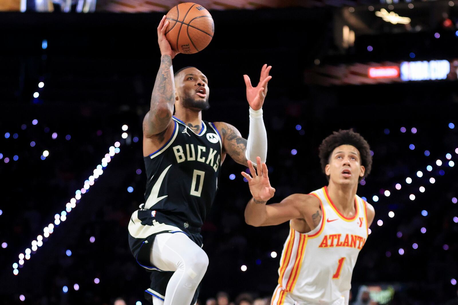 Milwaukee Bucks guard Damian Lillard (0) shoots against Atlanta Hawks forward Jalen Johnson (1) during the second half of a semifinal game in the NBA Cup basketball tournament Saturday, Dec. 14, 2024, in Las Vegas. (AP Photo/Ian Maule)