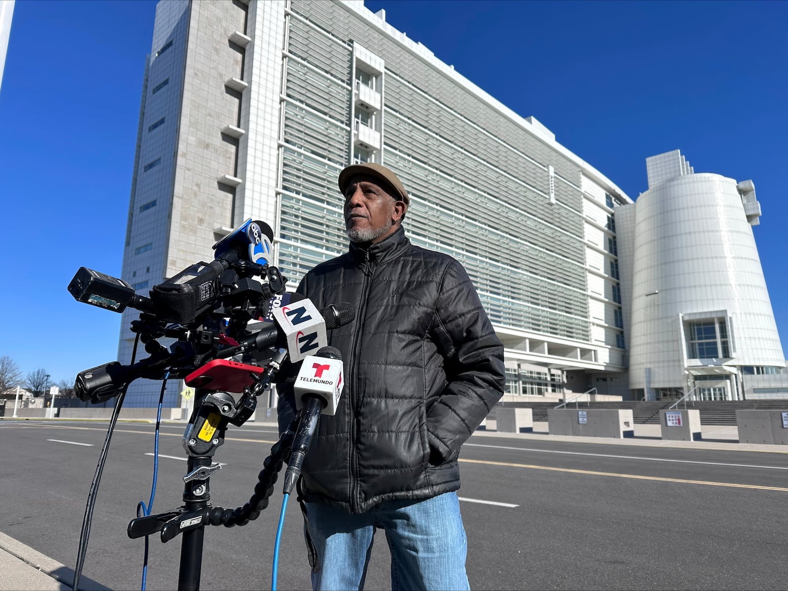 George Johnson, the father of Michael Johnson, a 29-year-old who was killed by MS-13 gang members in 2016, speaks outside the federal court, behind, in Central Islip, New York, where Jairo Saenz, a high-ranking member of a local MS-13 clique, pleaded guilty to racketeering and other federal charges on Tuesday, Jan. 14, 2025. (AP Photo/Philip Marcelo)