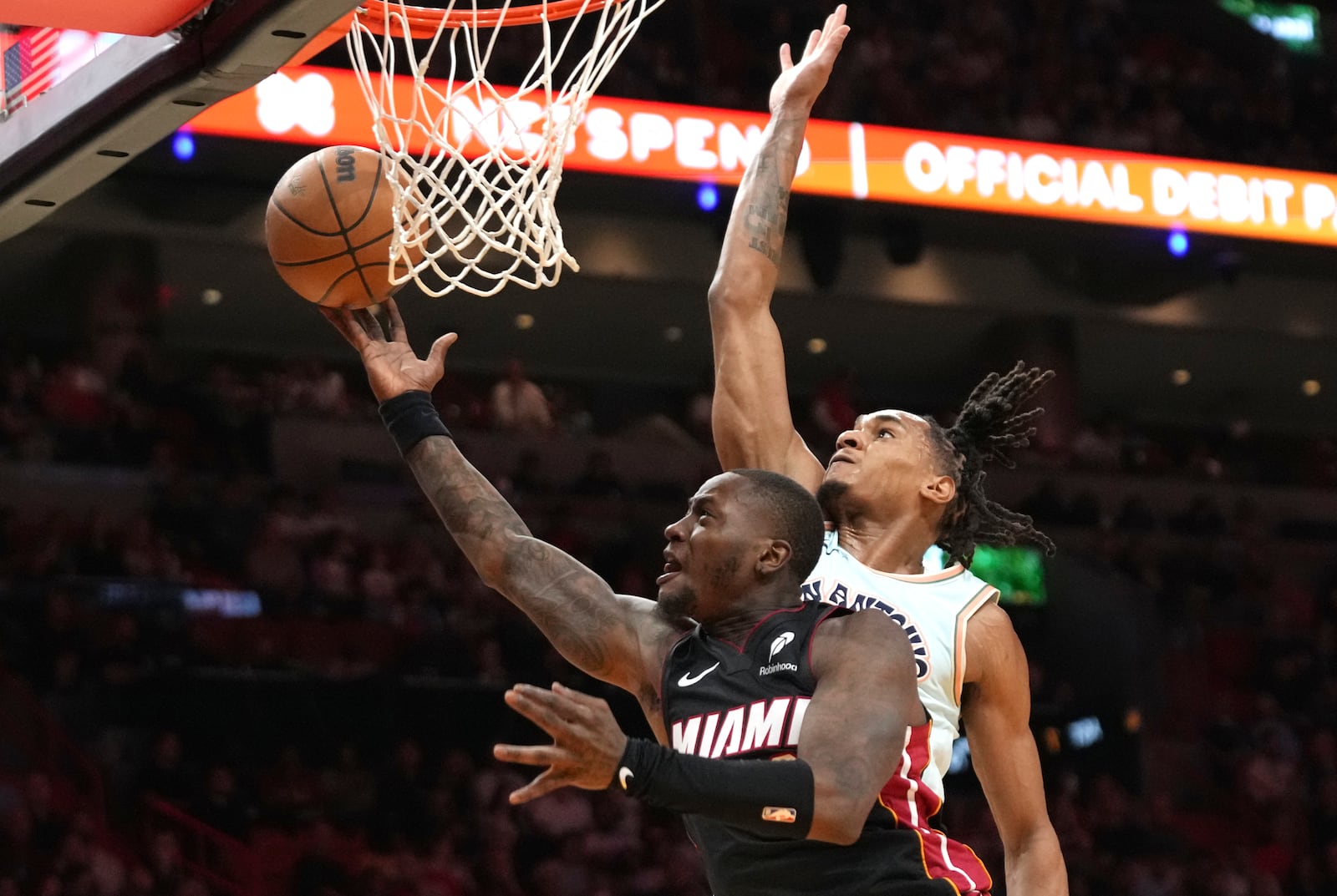 Miami Heat guard Terry Rozier, left, shoots as San Antonio Spurs guard Devin Vassell defends during the first half of an NBA basketball game, Sunday, Jan. 19, 2025, in Miami. (AP Photo/Lynne Sladky)