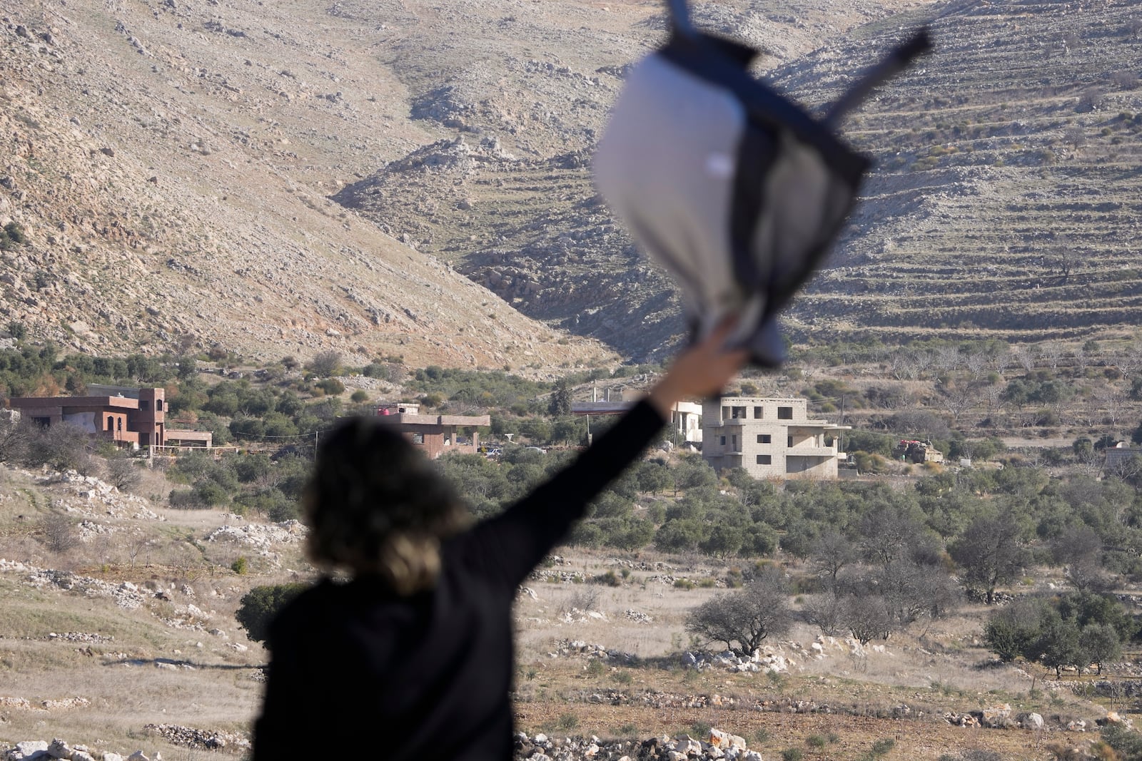 Salma Safadi waves to her sister, Sawsan, who is inside the buffer zone near the "Alpha Line" that separates the Israeli-controlled Golan Heights from Syria, in the town of Majdal Shams, Tuesday, Dec. 17, 2024. (AP Photo/Matias Delacroix)