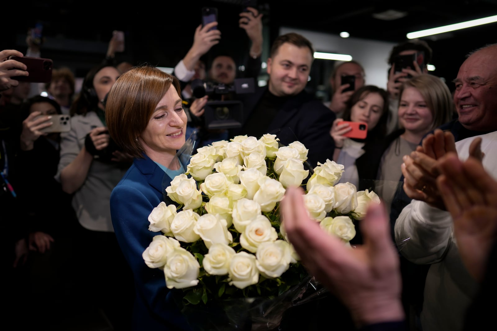 Moldova's President Maia Sandu smiles while holding a bouquet of flowers as she celebrates with supporters the preliminary results of the presidential election runoff, in Chisinau, Moldova, Sunday, Nov. 3, 2024. (AP Photo/Vadim Ghirda)