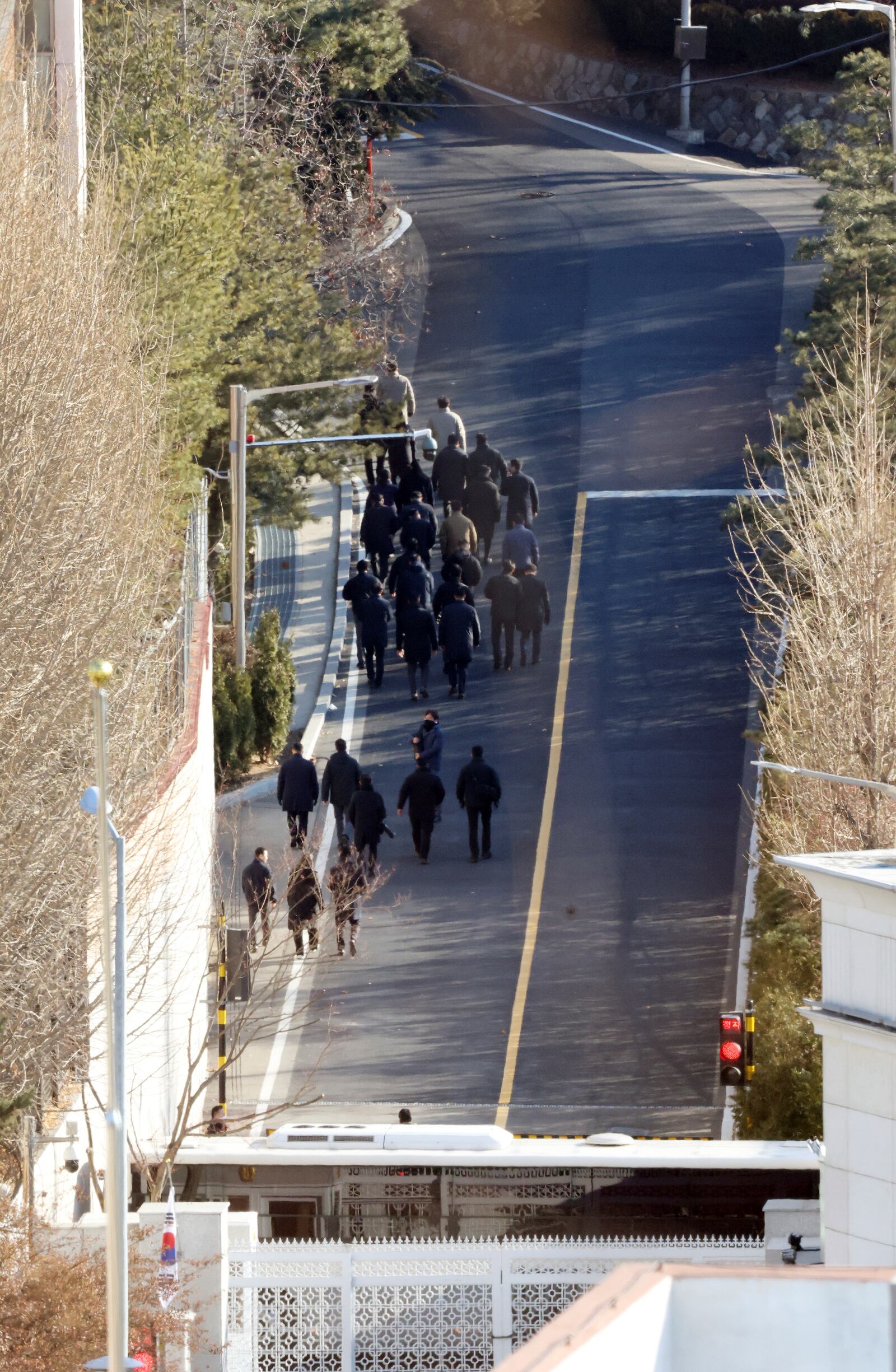 Investigators from the Corruption Investigation Office for High-ranking Officials walk up a slope inside the premises of impeached President Yoon Suk Yeol's residence in Seoul, South Korea, Friday, Jan. 3, 2025. (Lee Jin-wook/Yonhap via AP)