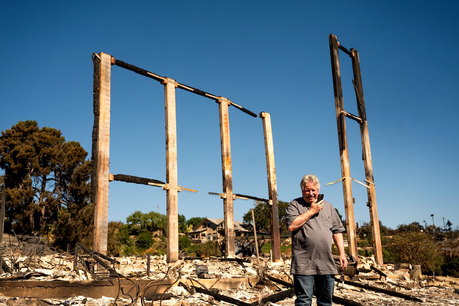 Joey Parish phones his wife, Friday, Nov. 8, 2024, while standing in front of his home, which was destroyed by the Mountain Fire in Camarillo, Calif. (AP Photo/Noah Berger)